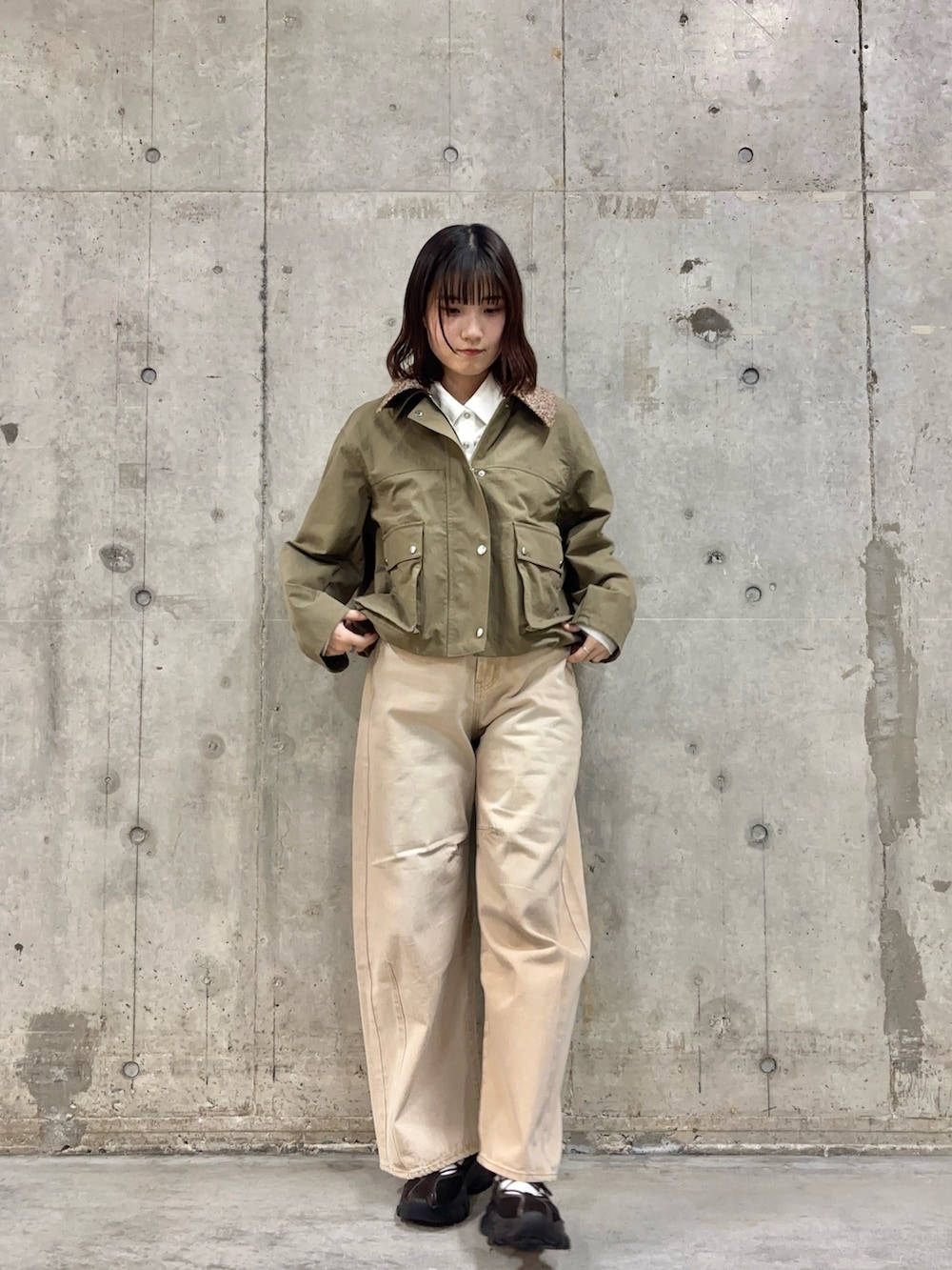 ベージュ系のデニムパンツ、グリーン系のブルゾン、ホワイト系のシャツ/ブラウスを着用したレディースの冬コーディネートの2枚目の写真