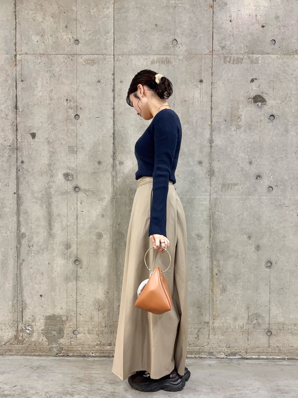 ブルー系のニット/セーター、ベージュ系のその他パンツ、イエロー系のハンドバッグを着用したレディースの秋コーディネートの3枚目の写真