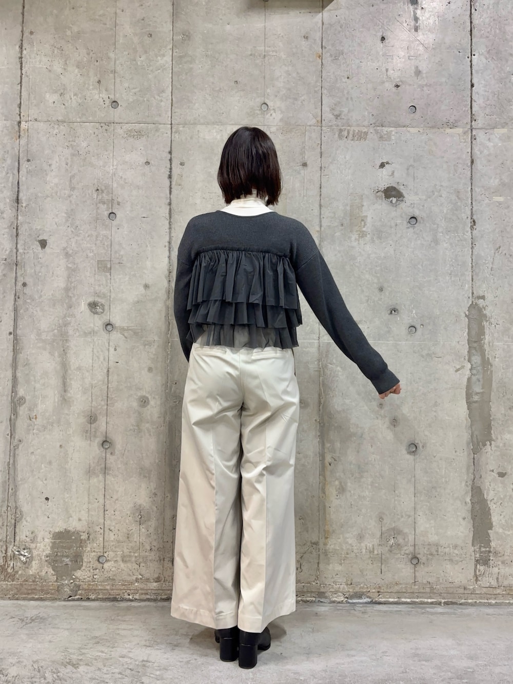 ホワイト系のチノパンツ、ブラック系のハンドバッグ、ブラック系のブーツを着用したレディースの冬コーディネートの3枚目の写真