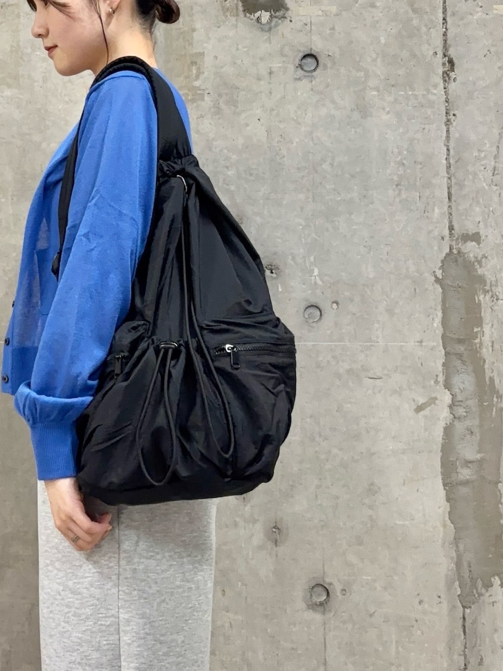 ブルー系のカーディガン/ボレロ、グレー系のその他パンツ、ブラック系のバックパック/リュックを着用したレディースの春コーディネートの2枚目の写真