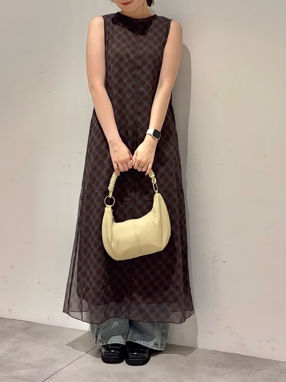 ブラウン系のワンピース、ブルー系のデニムパンツ、ベージュ系のハンドバッグを着用したレディースの春コーディネートの2枚目の写真