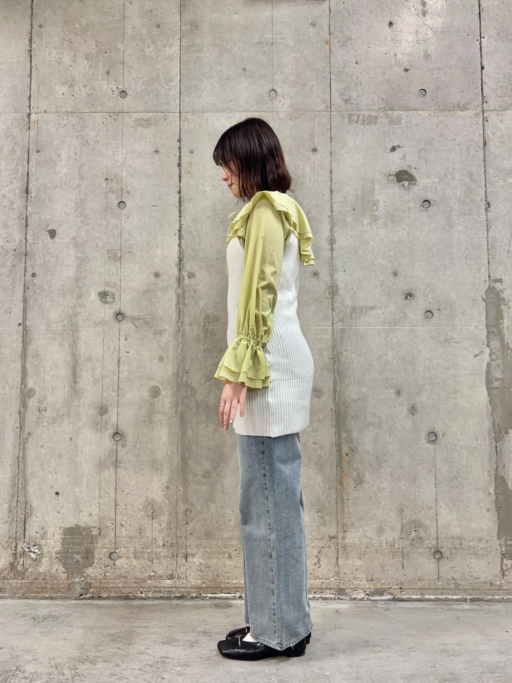 ブルー系のデニムパンツ、ブラック系のその他シューズ、ホワイト系のベストを着用したレディースの冬コーディネートの3枚目の写真