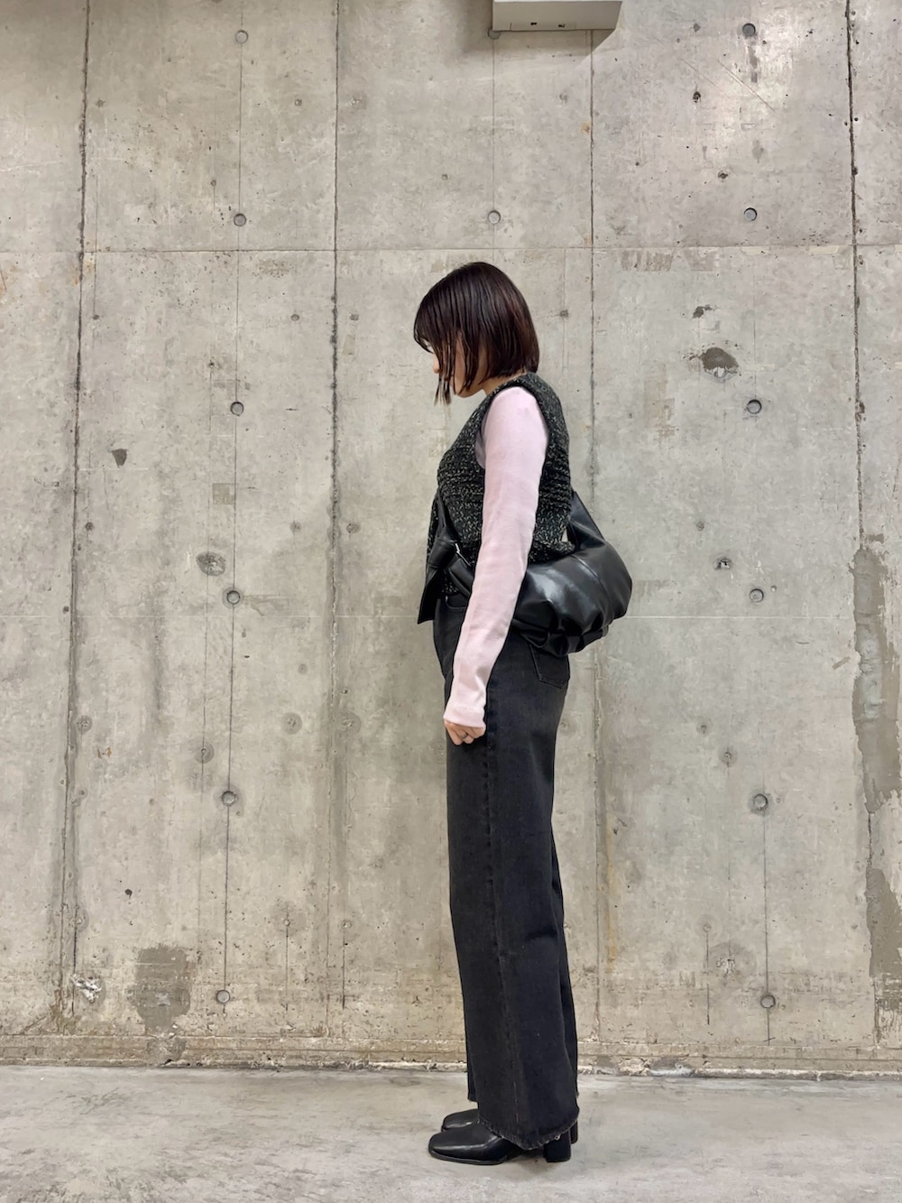 ブラック系のデニムパンツ、ブラック系のショルダーバッグ、ピンク系のTシャツ/カットソーを着用したレディースの冬コーディネートの3枚目の写真