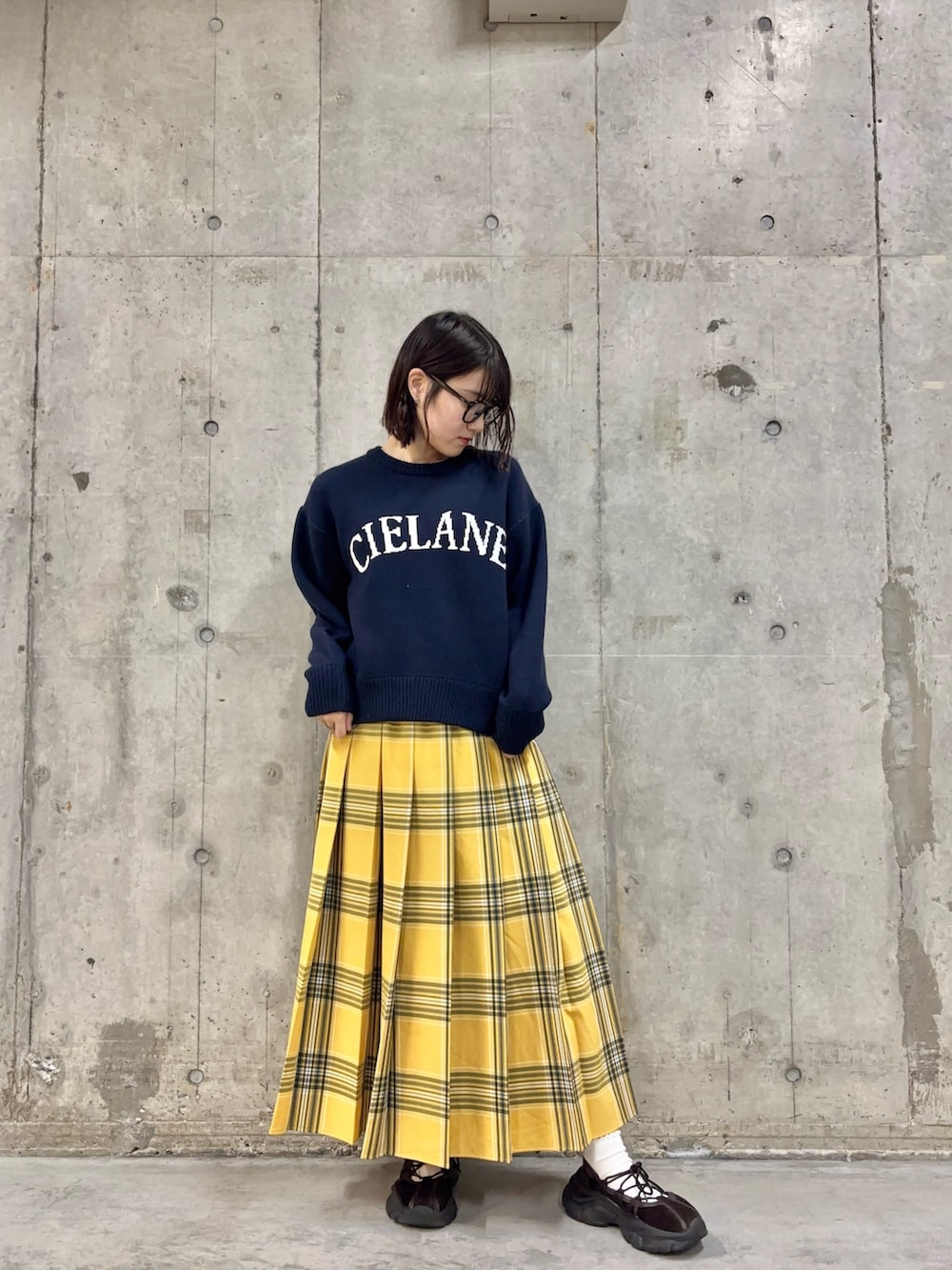 ブルー系のニット/セーター、イエロー系のスカート、ブラウン系のスニーカーを着用したレディースの冬コーディネートの2枚目の写真