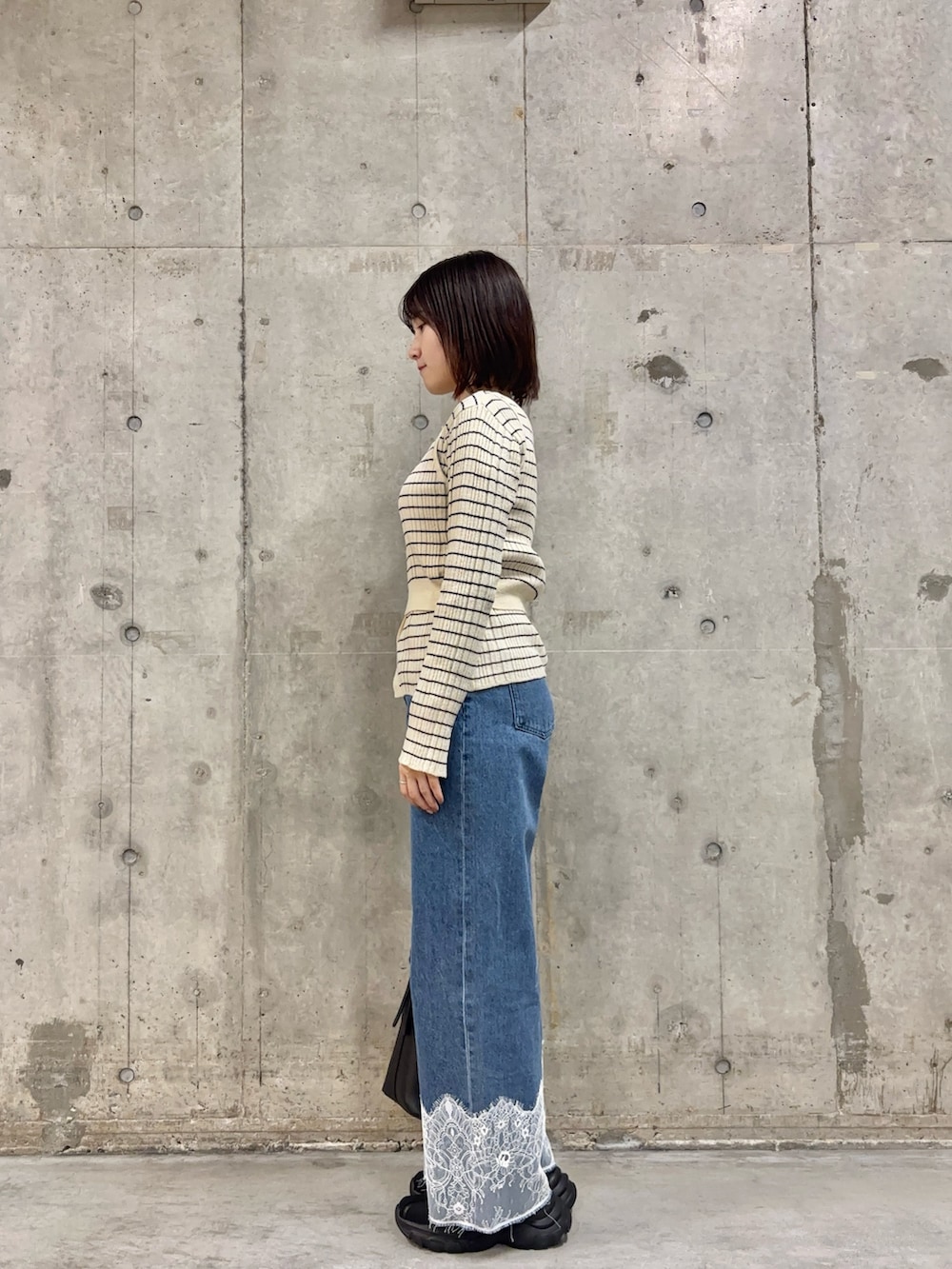 ホワイト系のニット/セーター、ブルー系のデニムパンツ、ブラック系のショルダーバッグを着用したレディースの冬コーディネートの2枚目の写真