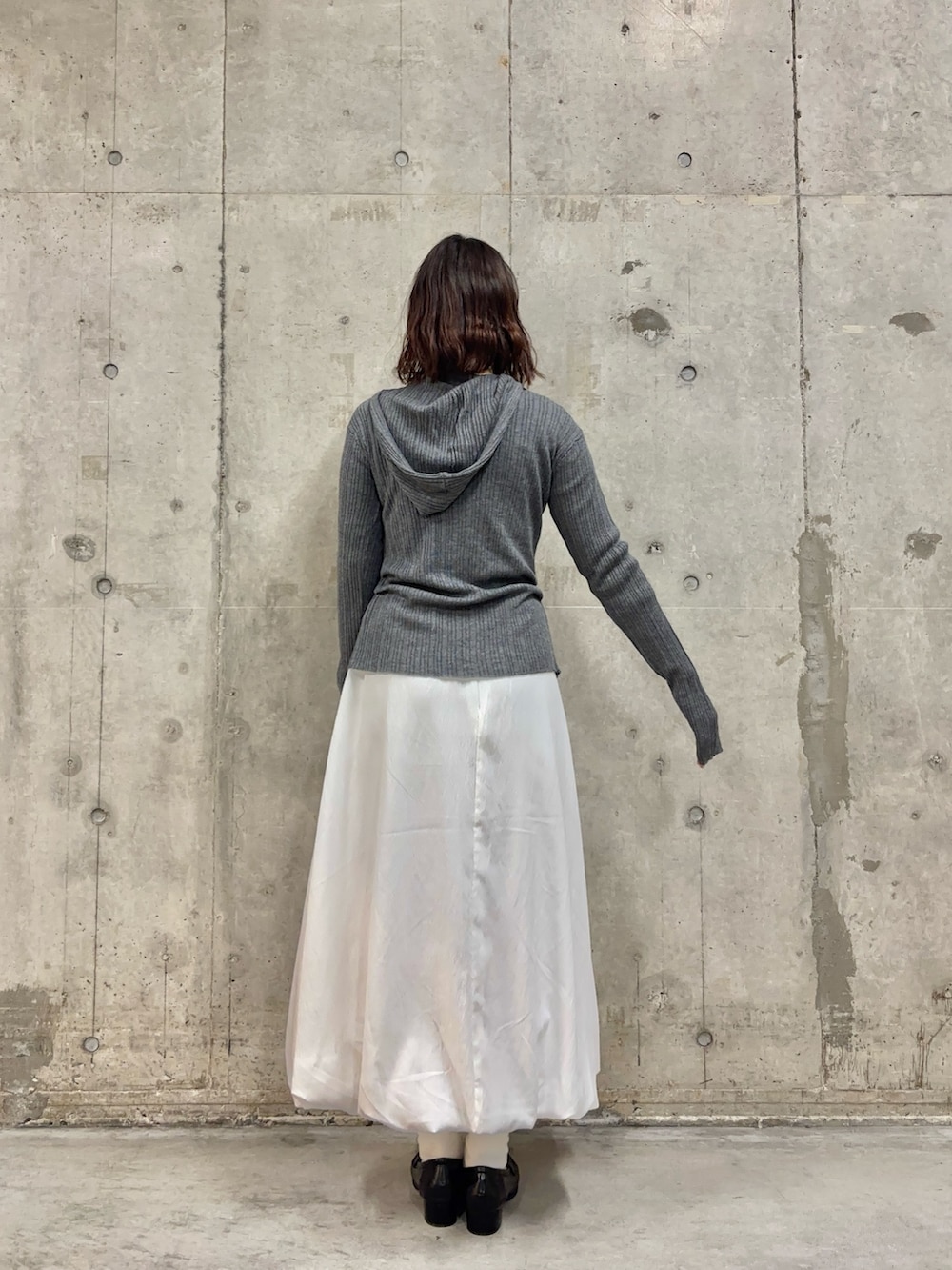 グレー系のニット/セーター、ブラウン系のローファー、ホワイト系のスカートを着用したレディースの春コーディネートの4枚目の写真