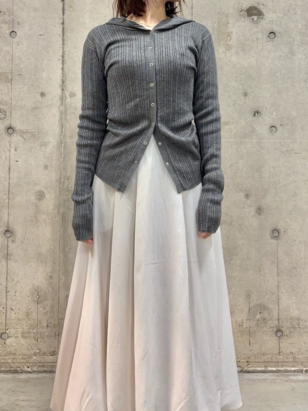 グレー系のニット/セーター、ブラウン系のローファー、ホワイト系のスカートを着用したレディースの春コーディネートの2枚目の写真