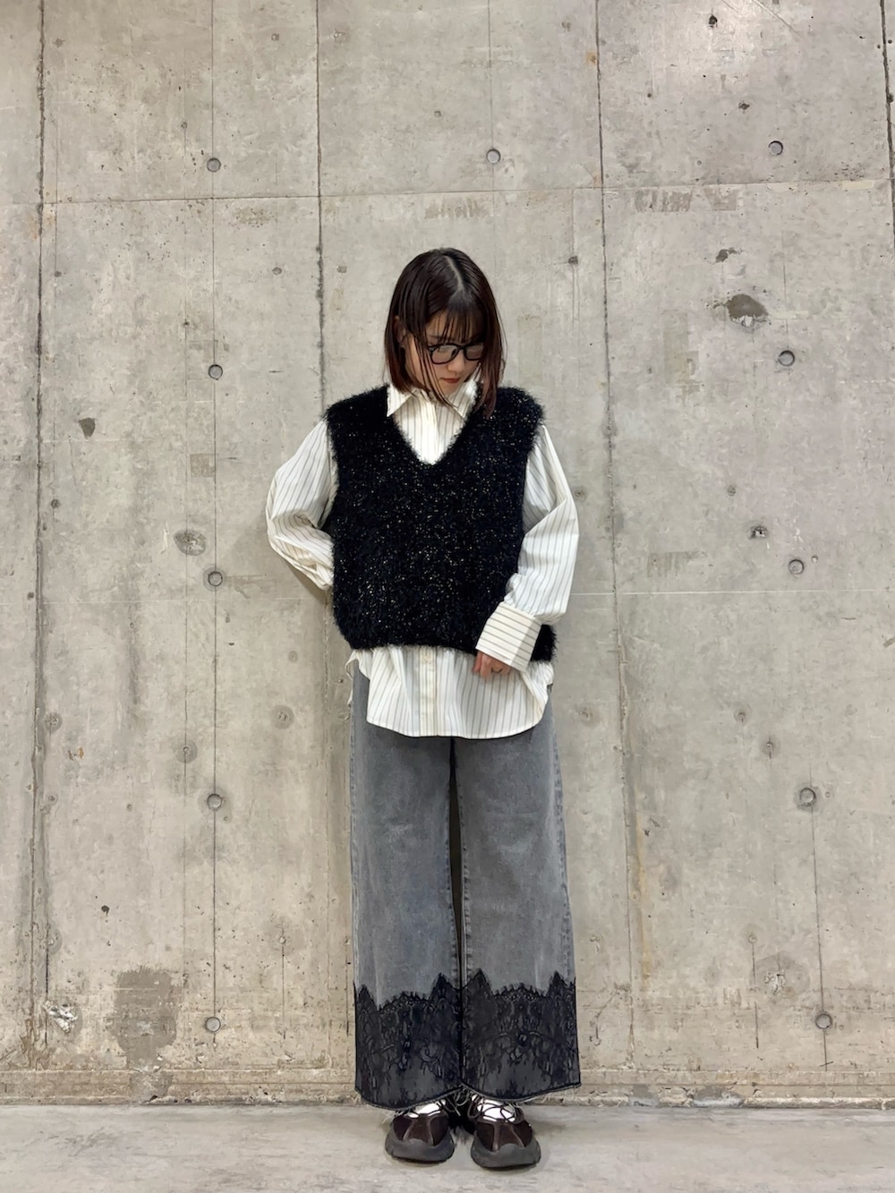 ブラック系のベスト、ブラウン系のスニーカー、グレー系のデニムパンツを着用したレディースの冬コーディネートの2枚目の写真