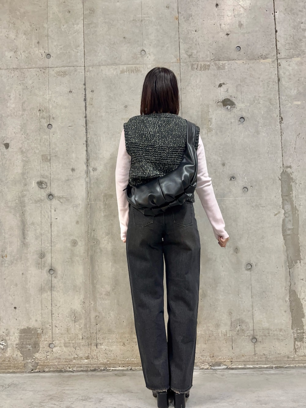 ブラック系のデニムパンツ、ブラック系のショルダーバッグ、ピンク系のTシャツ/カットソーを着用したレディースの冬コーディネートの4枚目の写真