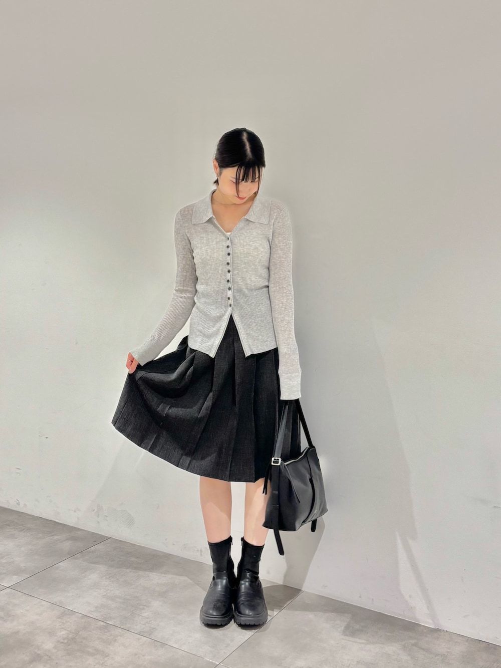 グレー系のカーディガン/ボレロ、ホワイト系のキャミソール、ブラック系のブーツを着用したレディースの秋コーディネートの2枚目の写真