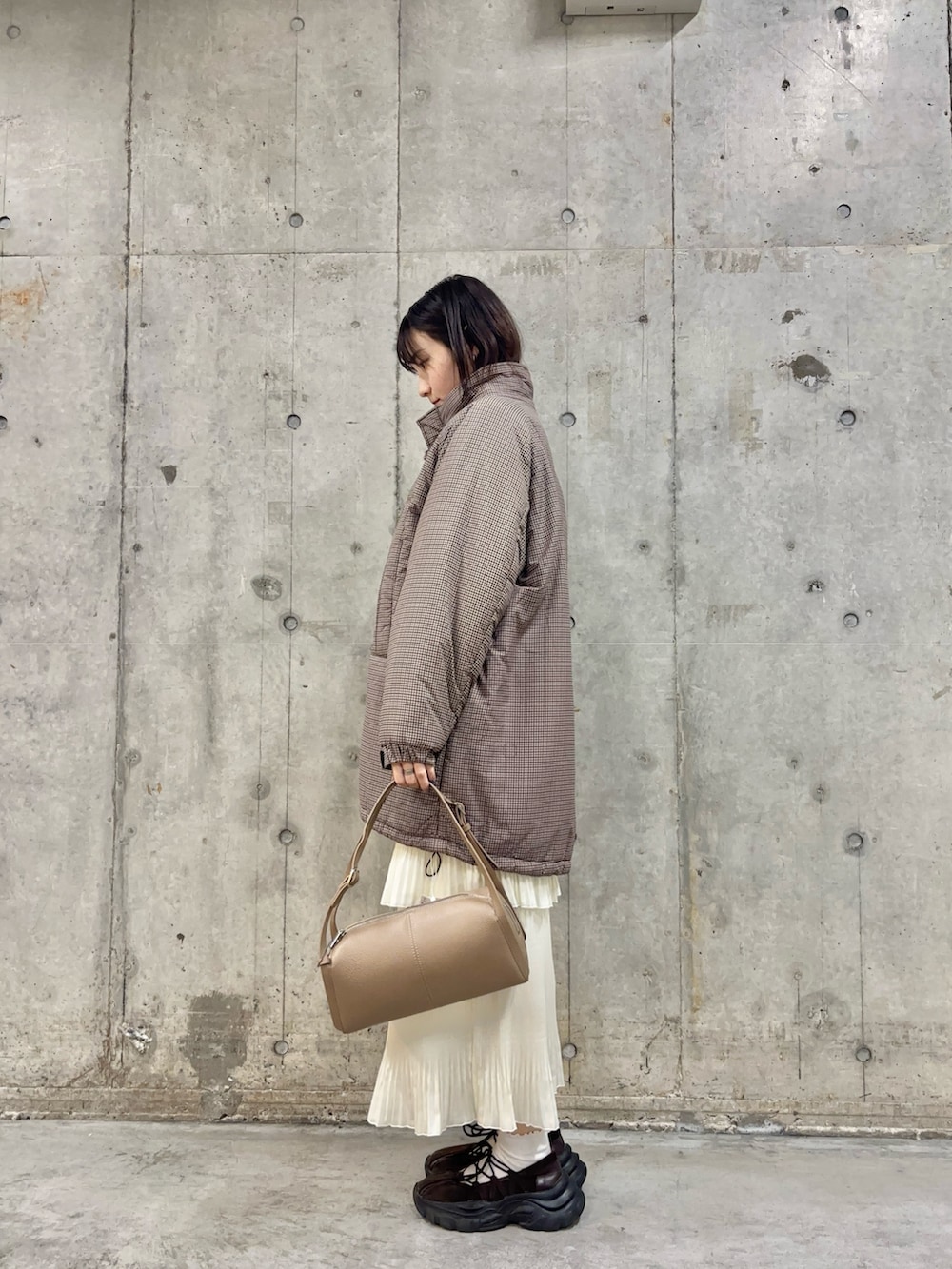 ブラウン系のスニーカー、ホワイト系のスカート、ベージュ系のボストンバッグを着用したレディースの冬コーディネートの4枚目の写真