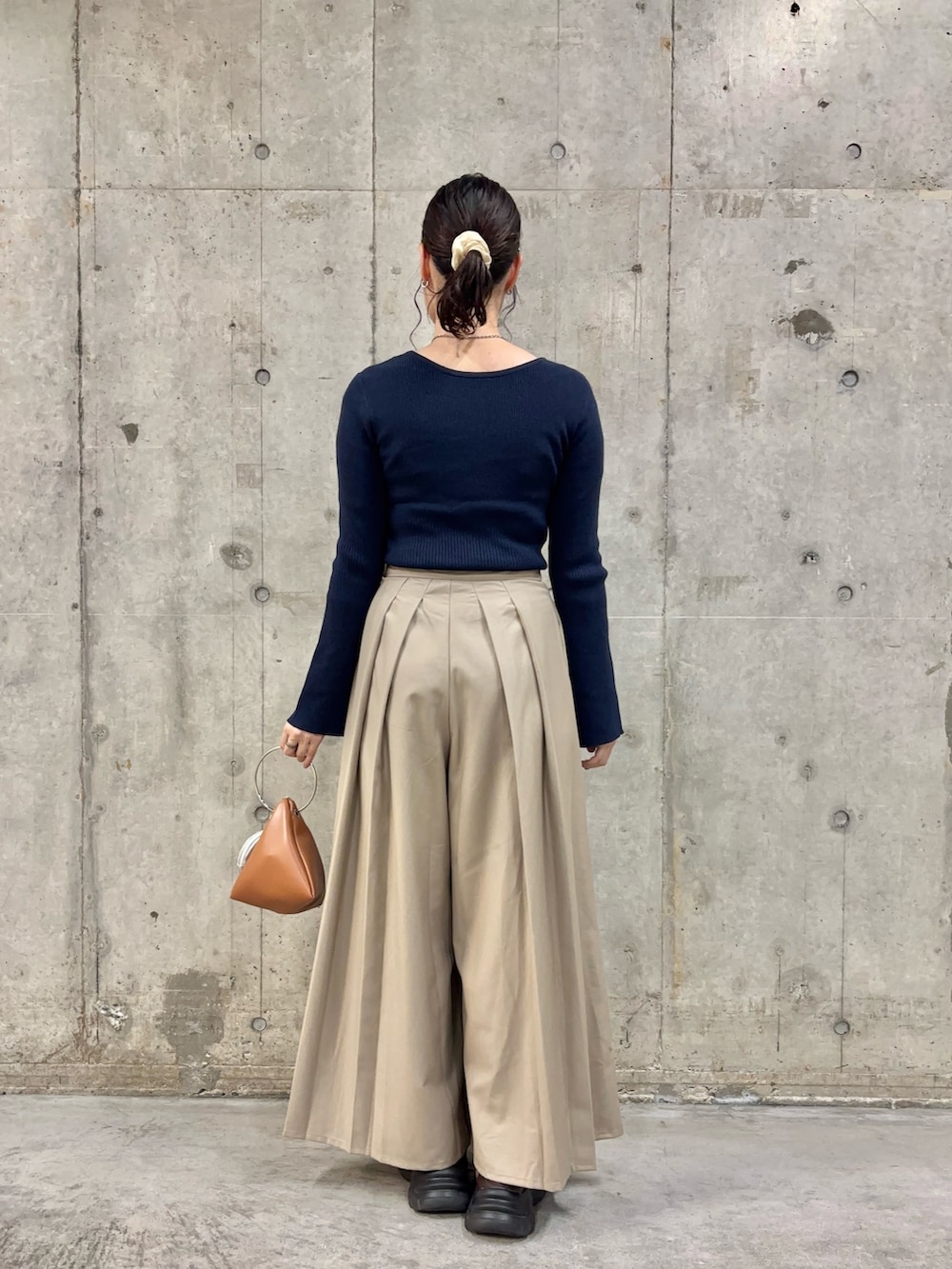 ブルー系のニット/セーター、ベージュ系のその他パンツ、イエロー系のハンドバッグを着用したレディースの秋コーディネートの4枚目の写真