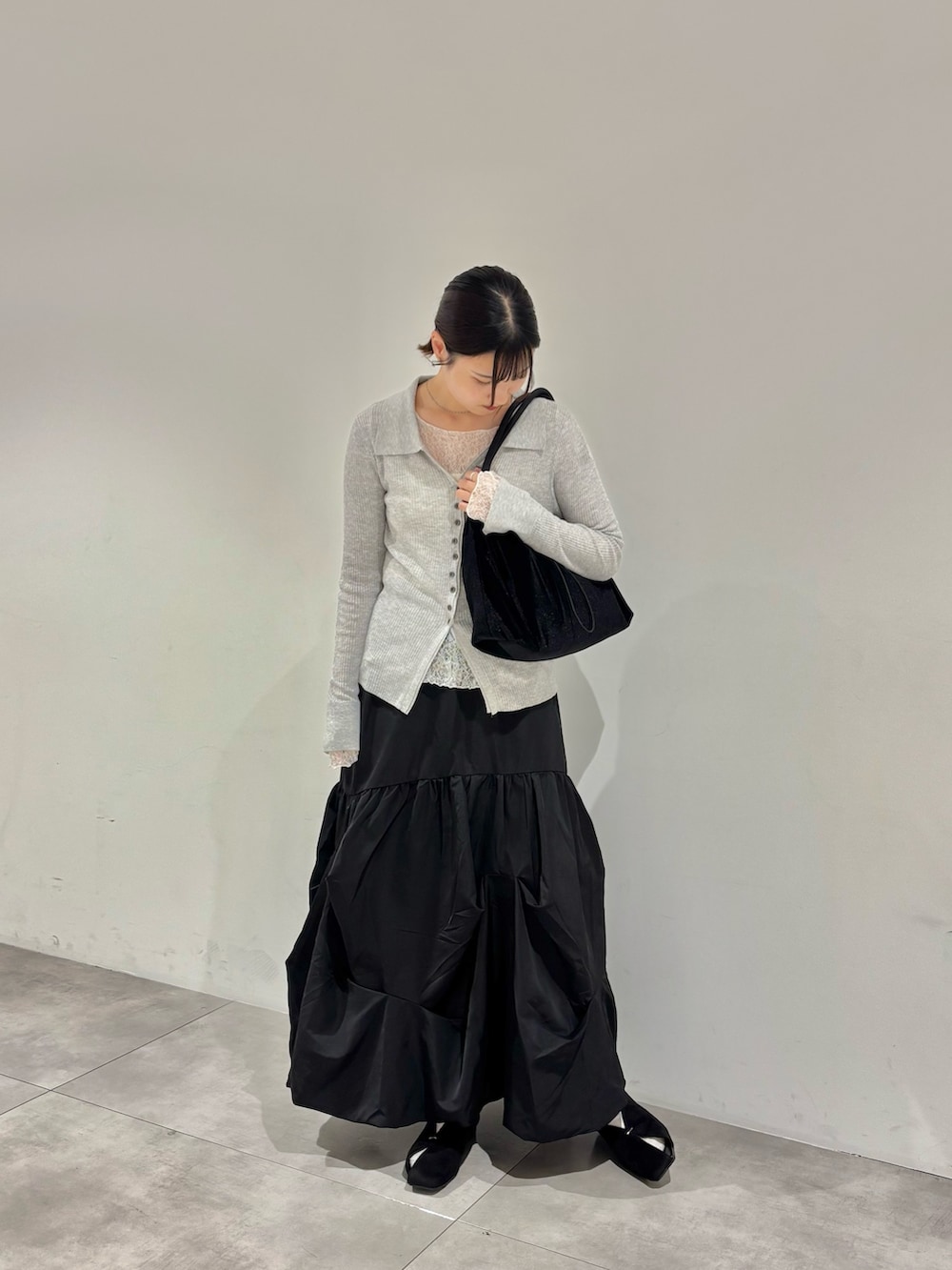 ホワイト系のTシャツ/カットソー、グレー系のカーディガン/ボレロ、ブラック系のスカートを着用したレディースの秋コーディネートの2枚目の写真