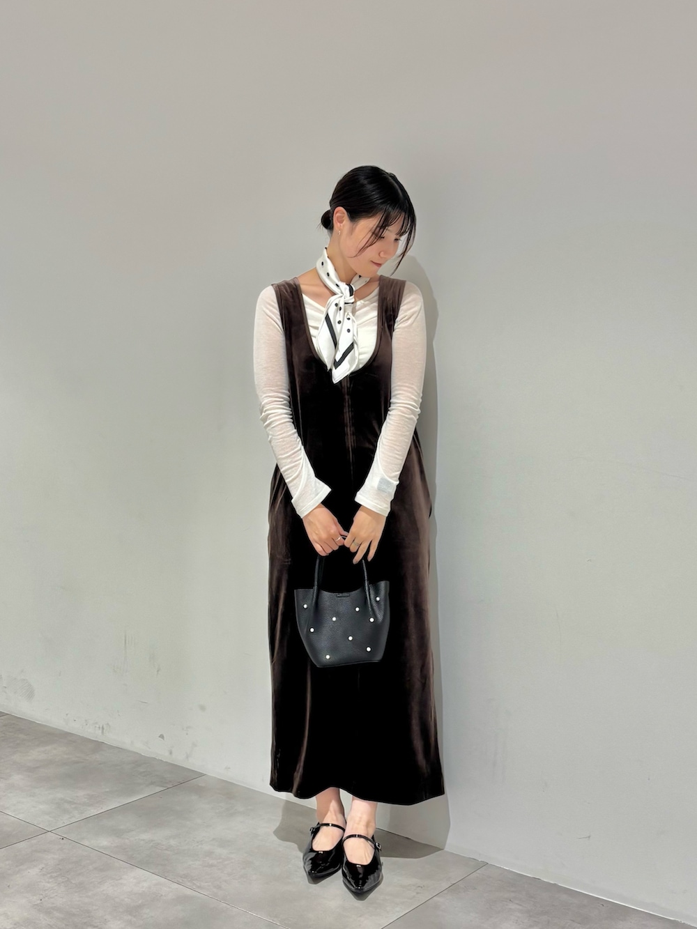 ブラウン系のワンピース、ホワイト系のTシャツ/カットソー、ブラック系のパンプスを着用したレディースの秋コーディネートの2枚目の写真