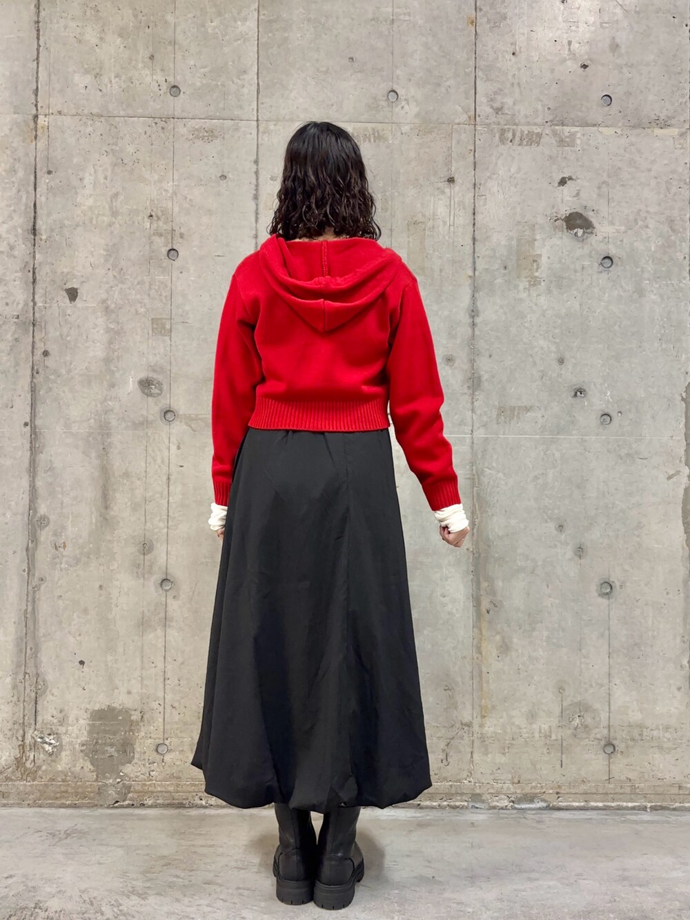 ブラック系のスカート、レッド系のニット/セーター、ブラック系のブーツを着用したレディースの冬コーディネートの4枚目の写真