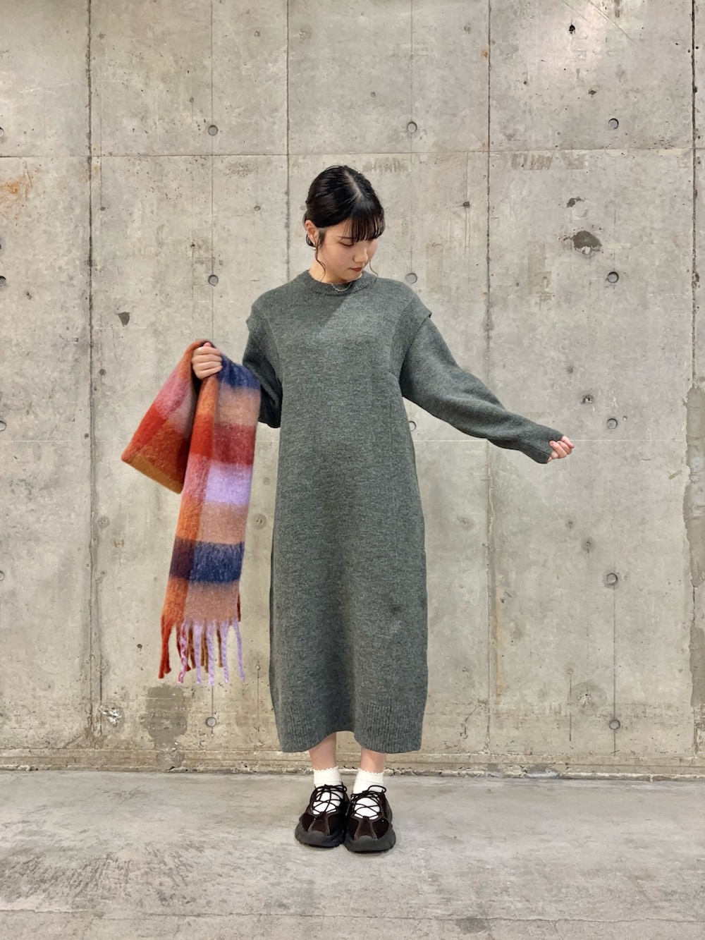 グレー系のワンピース、ブラウン系のスニーカー、オレンジ系のマフラーを着用したレディースの秋コーディネートの2枚目の写真