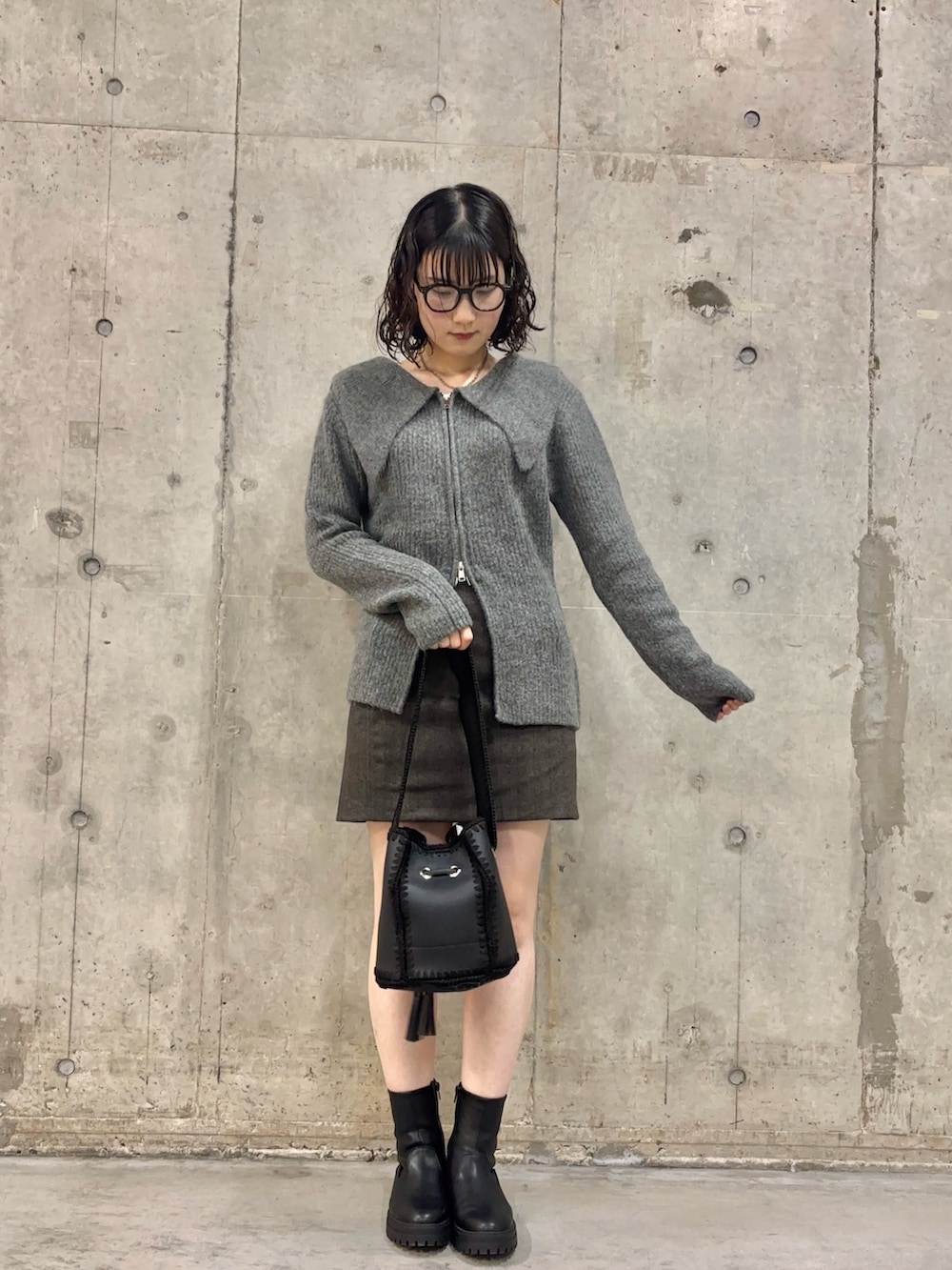 ブラック系のブーツ、ブラウン系のスカート、ブラック系のショルダーバッグを着用したレディースの秋コーディネートの2枚目の写真