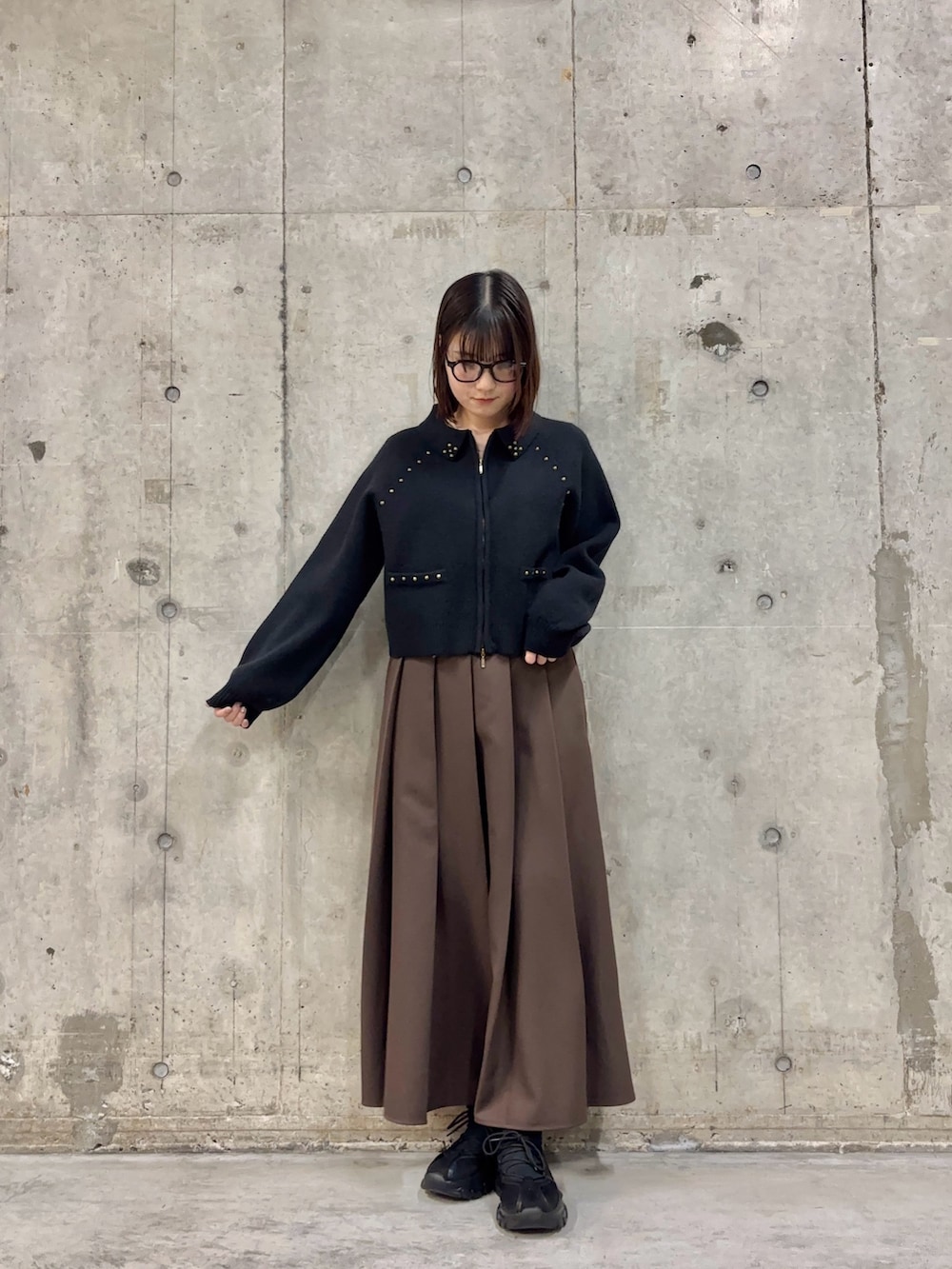 ブラウン系のスカート、ブラック系のカーディガン/ボレロ、ブラック系のスニーカーを着用したレディースの冬コーディネートの2枚目の写真