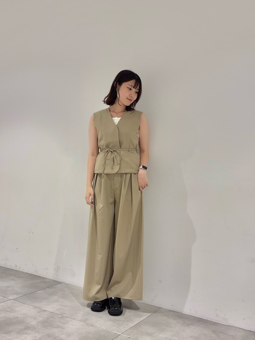 ベージュ系のスラックス、ホワイト系のタンクトップ、ベージュ系のベストを着用したレディースの夏コーディネートの2枚目の写真