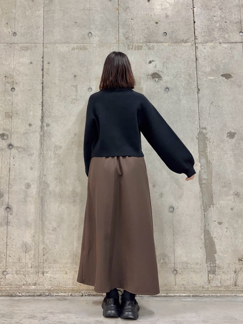 ブラウン系のスカート、ブラック系のカーディガン/ボレロ、ブラック系のスニーカーを着用したレディースの冬コーディネートの4枚目の写真