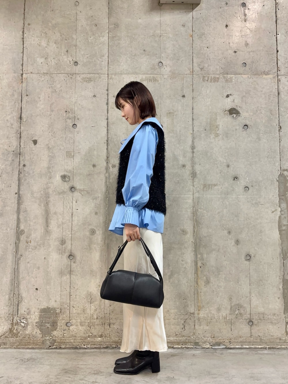 ブラック系のベスト、ブルー系のシャツ/ブラウス、ブラック系のボストンバッグを着用したレディースの冬コーディネートの3枚目の写真