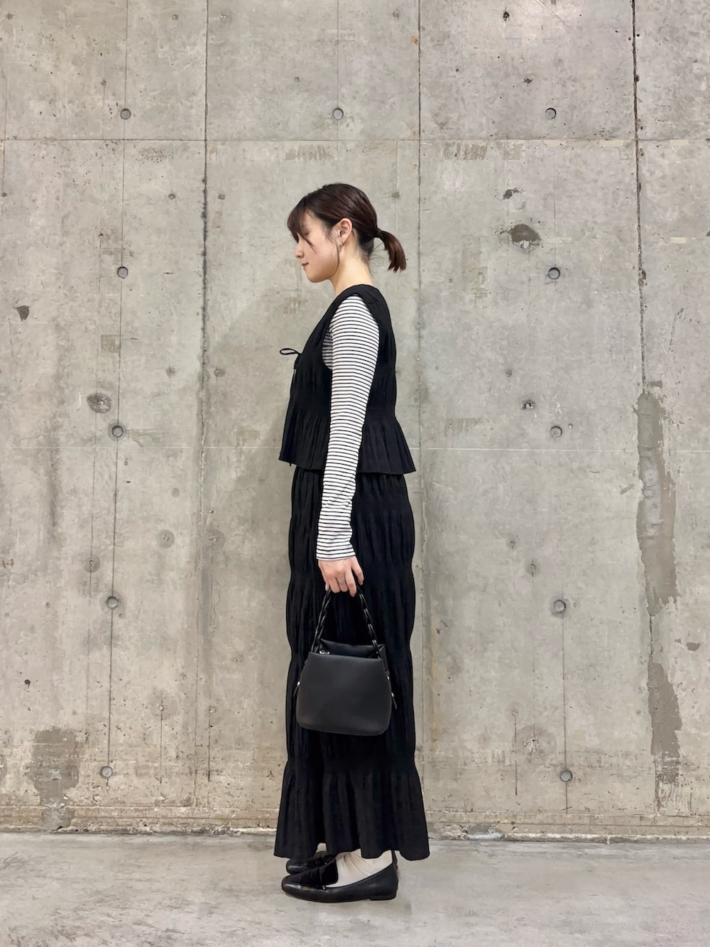 ブラック系のセットアップ、ホワイト系のTシャツ/カットソー、ブラック系のショルダーバッグを着用したレディースの春コーディネートの3枚目の写真