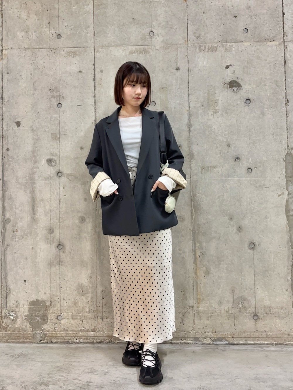 グレー系のテーラードジャケット、ホワイト系のTシャツ/カットソー、ホワイト系のスカートを着用したレディースの春コーディネートの2枚目の写真