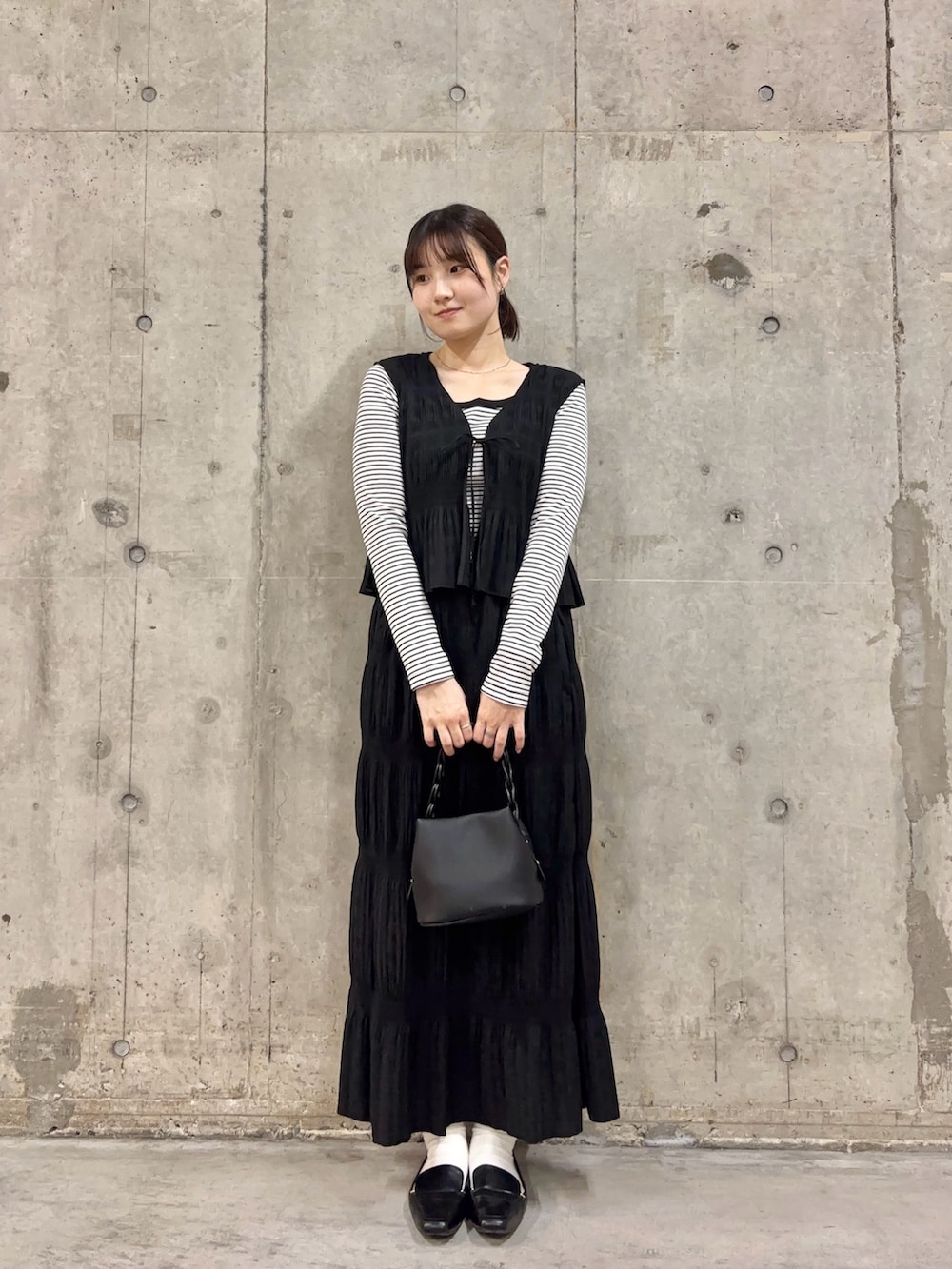ブラック系のセットアップ、ホワイト系のTシャツ/カットソー、ブラック系のショルダーバッグを着用したレディースの春コーディネートの2枚目の写真