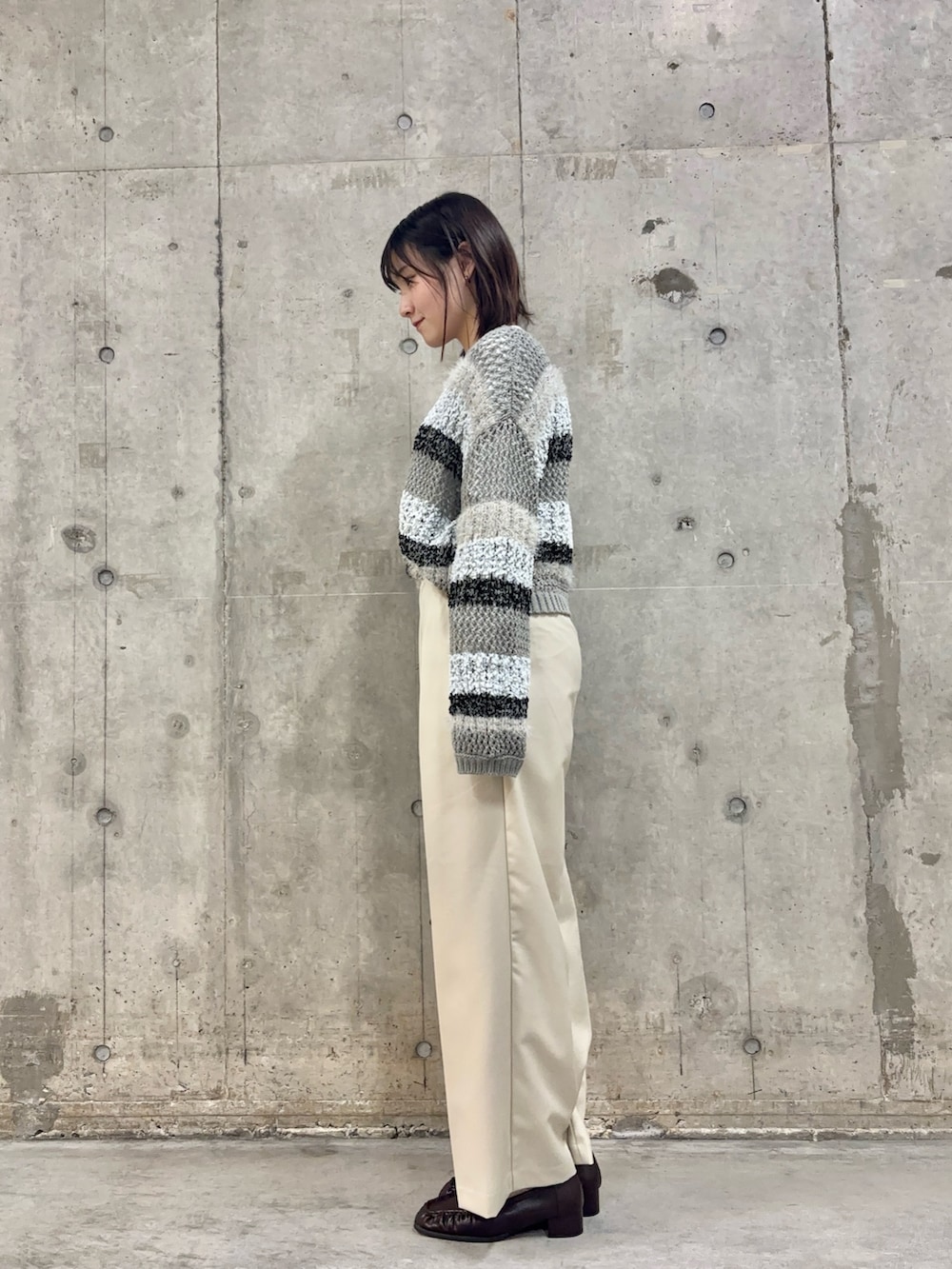 グレー系のニット/セーター、ブラウン系のハンドバッグ、その他のTシャツ/カットソーを着用したレディースの冬コーディネートの2枚目の写真