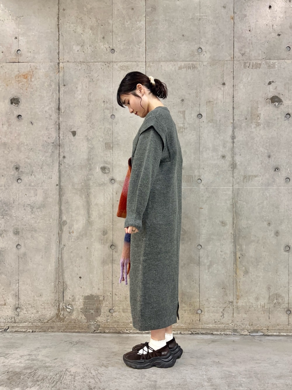 グレー系のワンピース、ブラウン系のスニーカー、オレンジ系のマフラーを着用したレディースの秋コーディネートの3枚目の写真