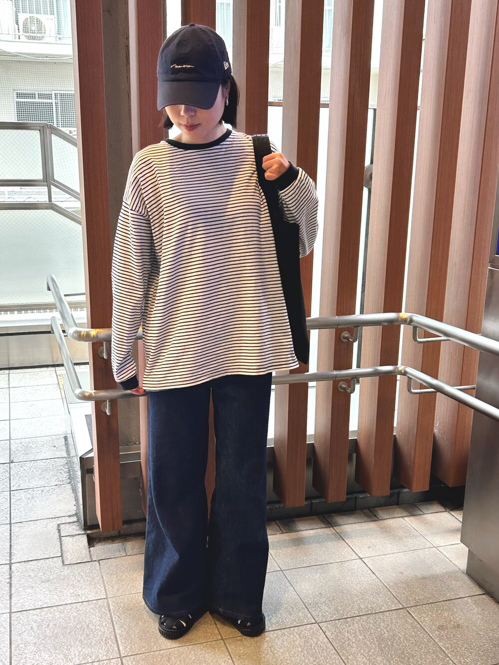 ブラック系のTシャツ/カットソー、ブラック系のトートバッグ、その他のデニムパンツを着用したレディースの春コーディネートの2枚目の写真