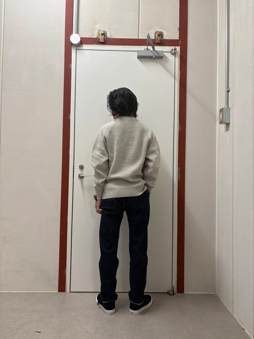 ブルー系のデニムパンツ、ホワイト系のニット/セーター、ブラック系のスニーカーを着用したメンズの冬コーディネートの3枚目の写真