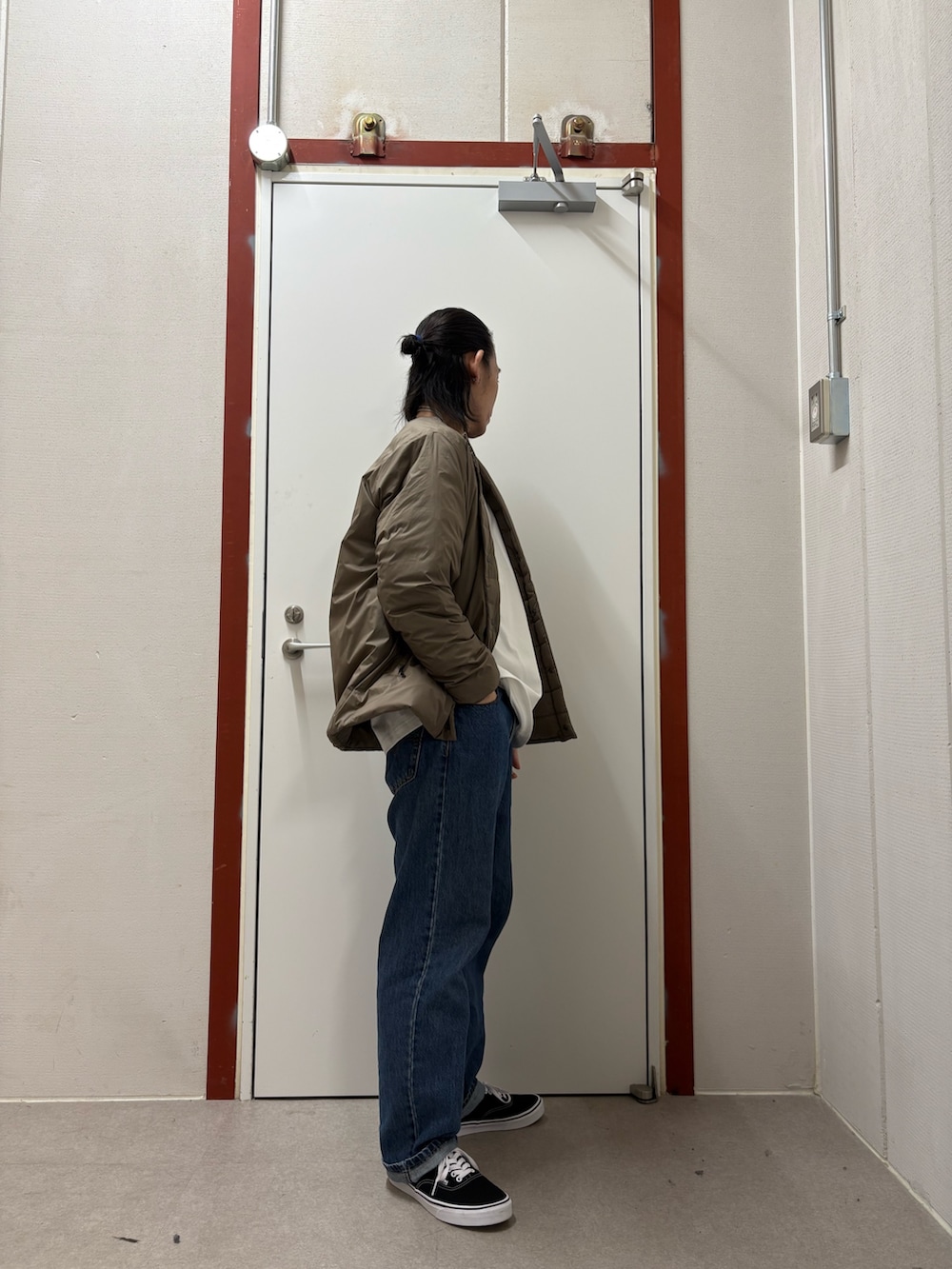 ブラウン系のダウンジャケット/コート、ホワイト系のTシャツ/カットソー、ブルー系のデニムパンツを着用したメンズの秋コーディネートの2枚目の写真