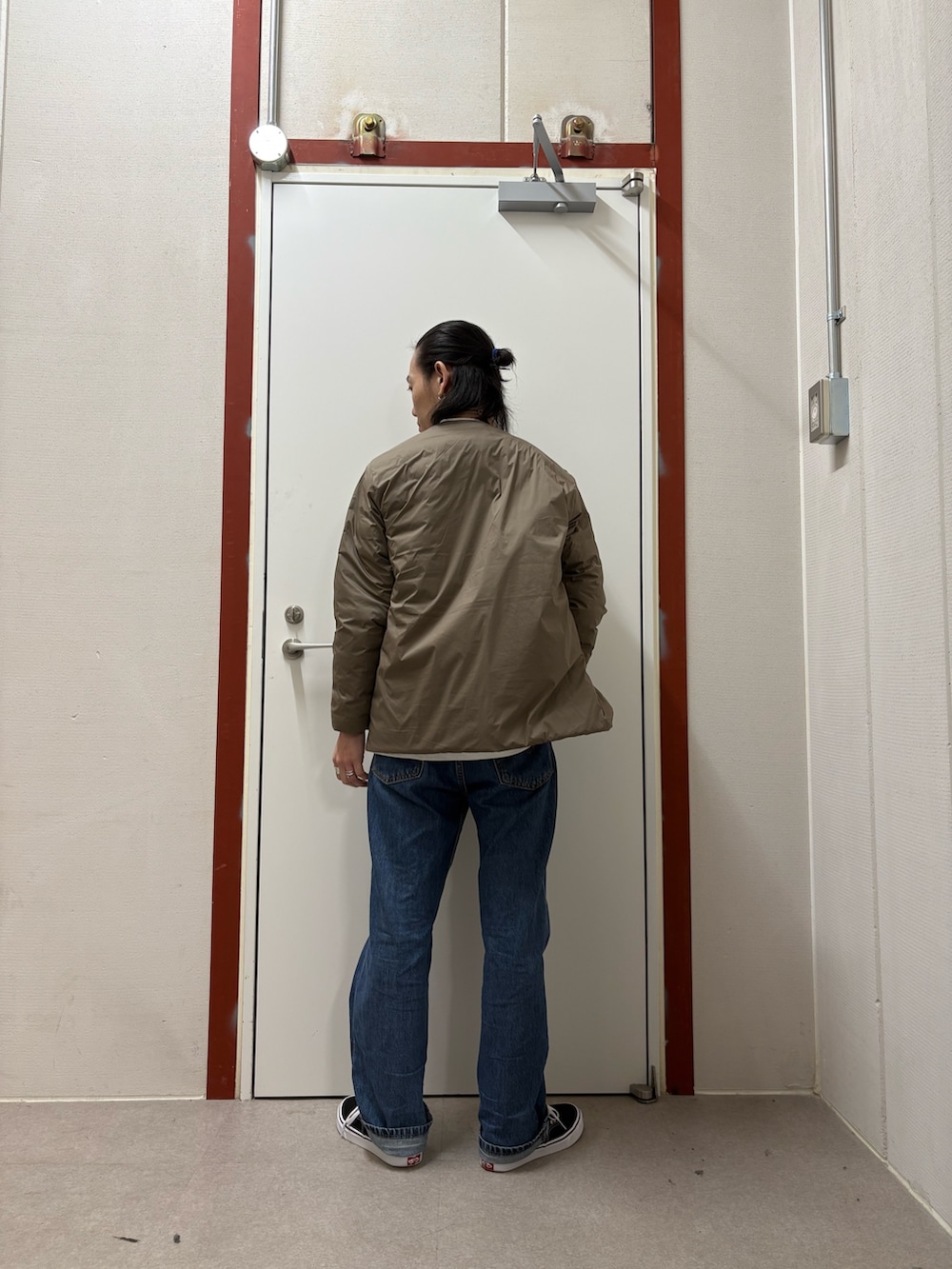 ブラウン系のダウンジャケット/コート、ホワイト系のTシャツ/カットソー、ブルー系のデニムパンツを着用したメンズの秋コーディネートの3枚目の写真