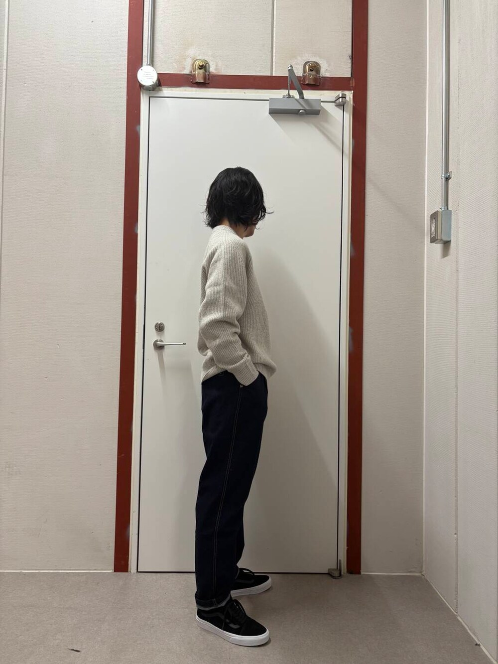 ブルー系のデニムパンツ、ホワイト系のニット/セーター、ブラック系のスニーカーを着用したメンズの冬コーディネートの2枚目の写真