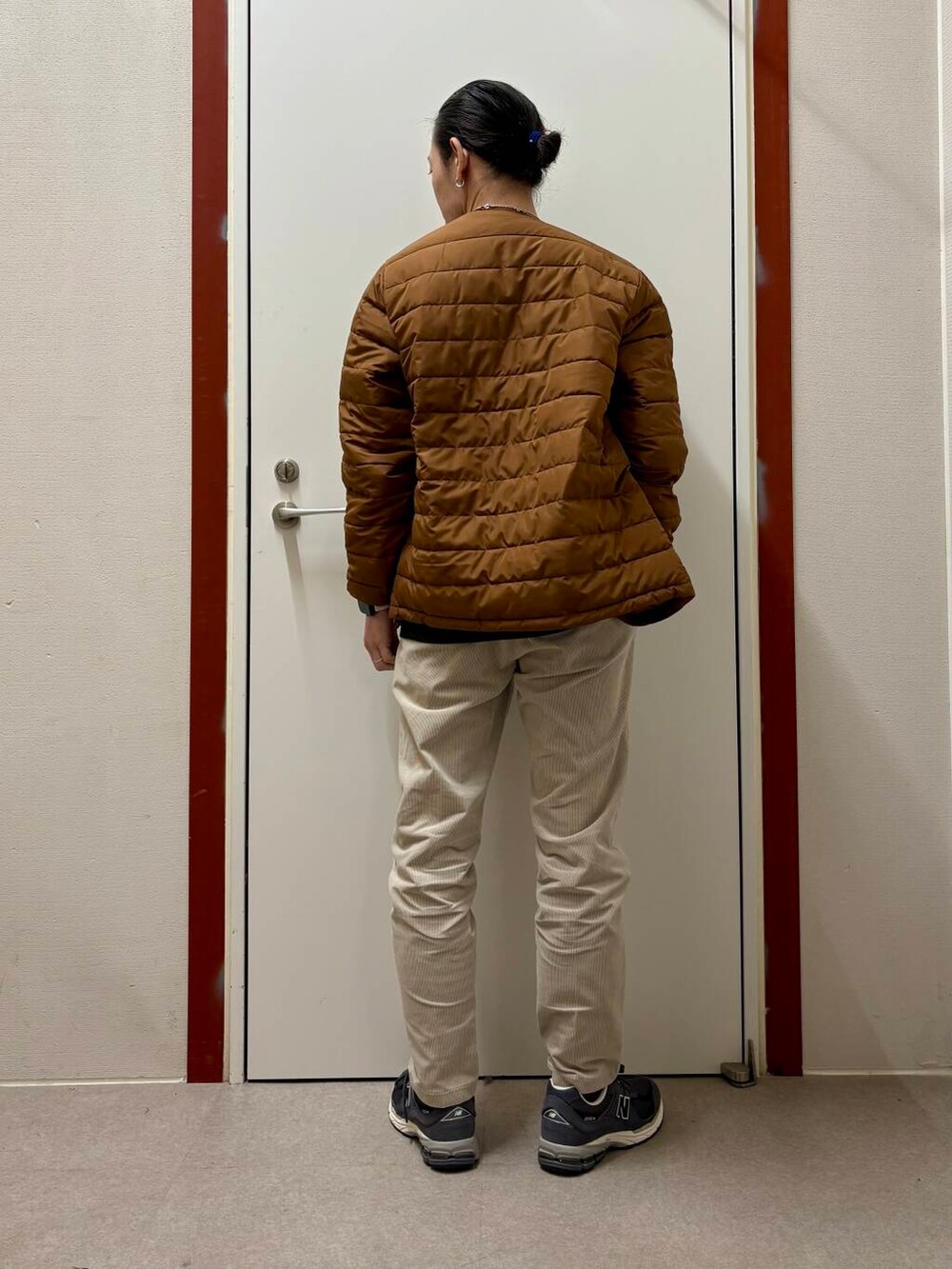 ホワイト系のその他パンツ、グレー系のニット/セーター、オレンジ系のダウンジャケット/コートを着用したメンズの秋コーディネートの3枚目の写真