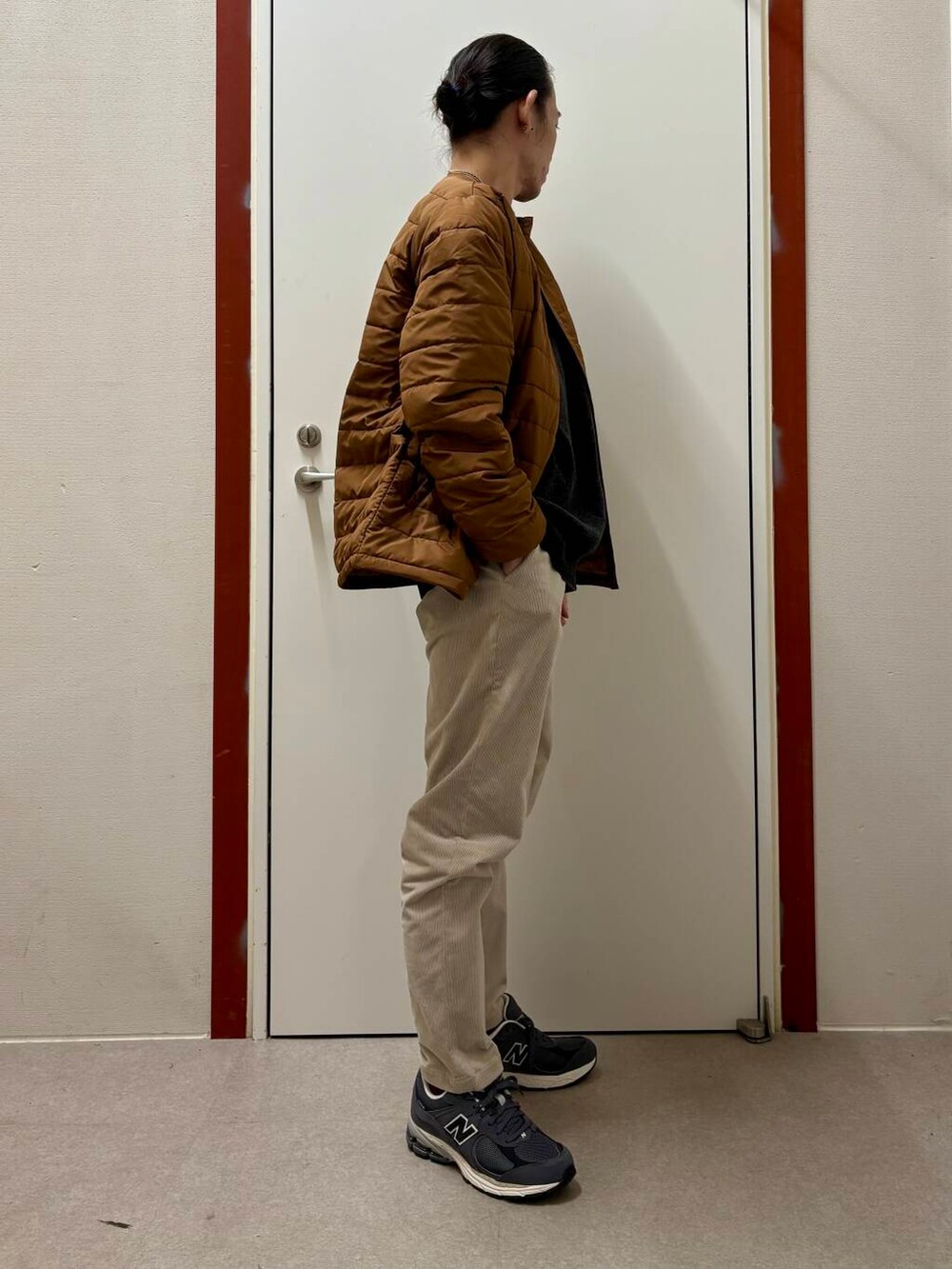 ホワイト系のその他パンツ、グレー系のニット/セーター、オレンジ系のダウンジャケット/コートを着用したメンズの秋コーディネートの2枚目の写真