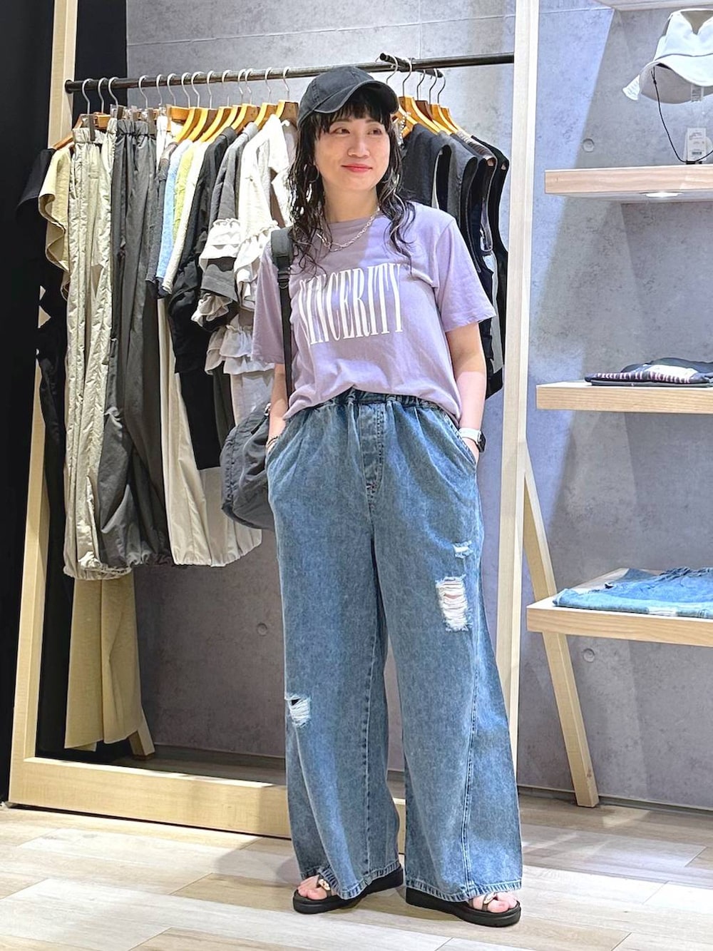 ブルー系のデニムパンツ、ブラウン系のサンダル、グレー系のバックパック/リュックを着用したレディースの夏コーディネートの2枚目の写真
