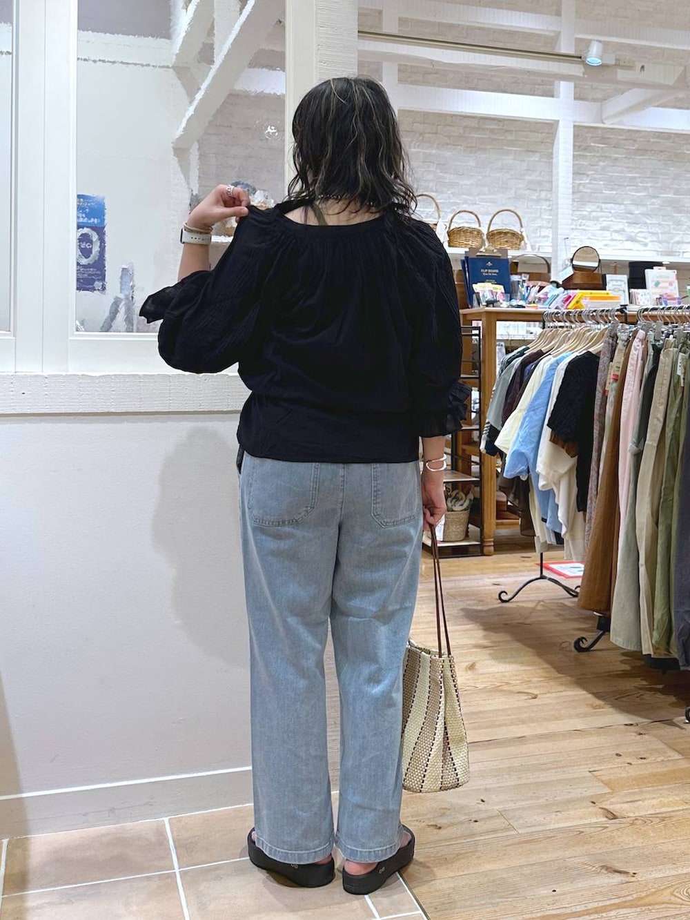 グリーン系のキャミソール、パープル系のトートバッグ、ブルー系のデニムパンツを着用したレディースの秋コーディネートの4枚目の写真