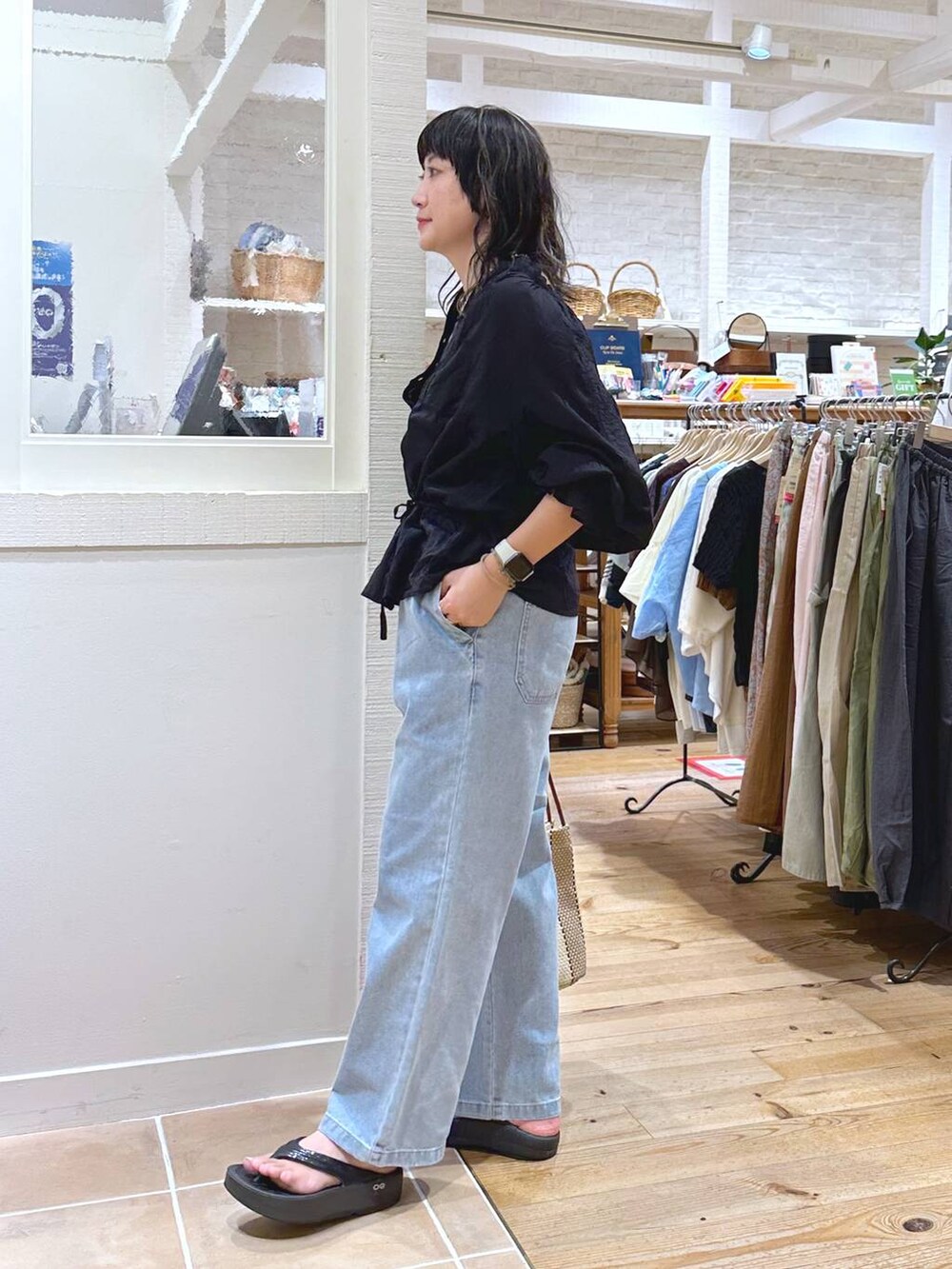 グリーン系のキャミソール、パープル系のトートバッグ、ブルー系のデニムパンツを着用したレディースの秋コーディネートの5枚目の写真