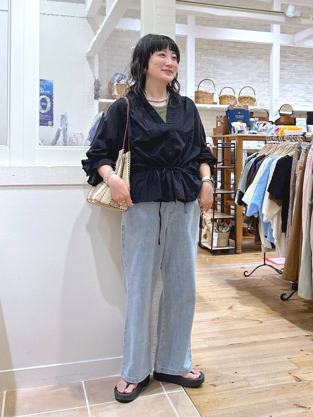 グリーン系のキャミソール、パープル系のトートバッグ、ブルー系のデニムパンツを着用したレディースの秋コーディネートの2枚目の写真