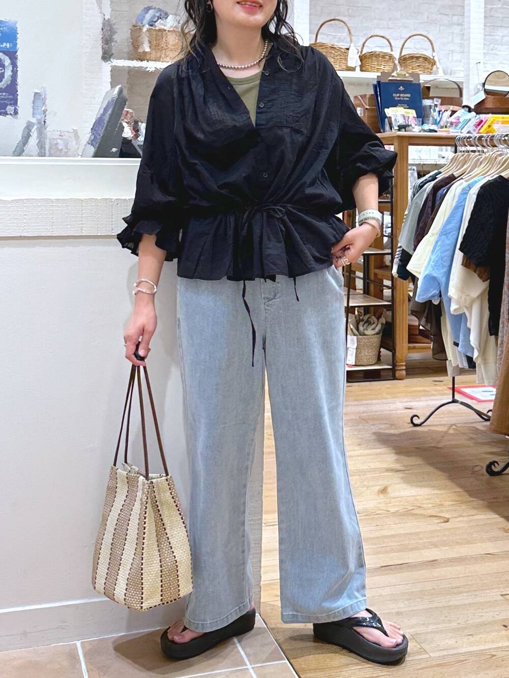 グリーン系のキャミソール、パープル系のトートバッグ、ブルー系のデニムパンツを着用したレディースの秋コーディネートの6枚目の写真