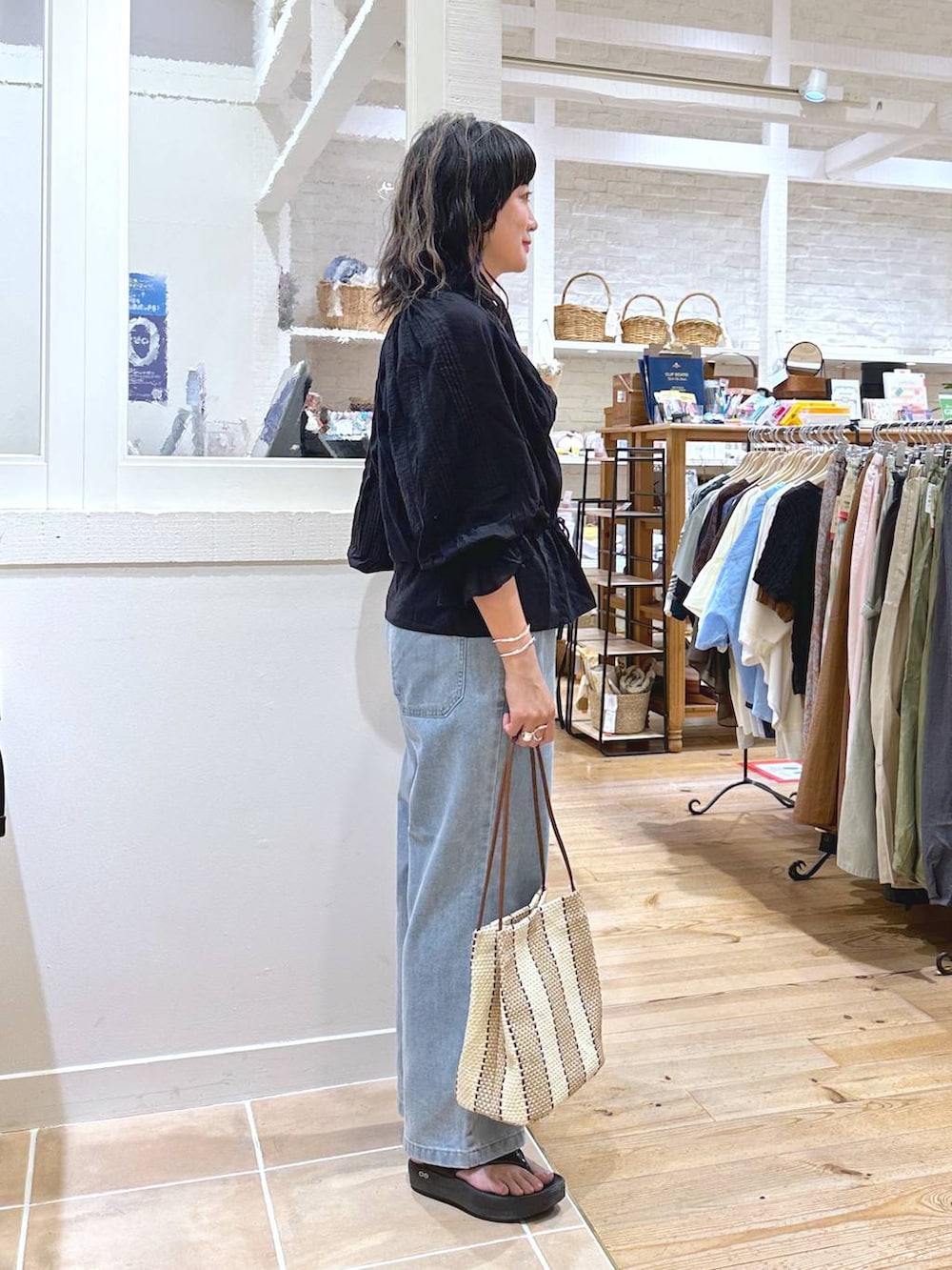 グリーン系のキャミソール、パープル系のトートバッグ、ブルー系のデニムパンツを着用したレディースの秋コーディネートの3枚目の写真