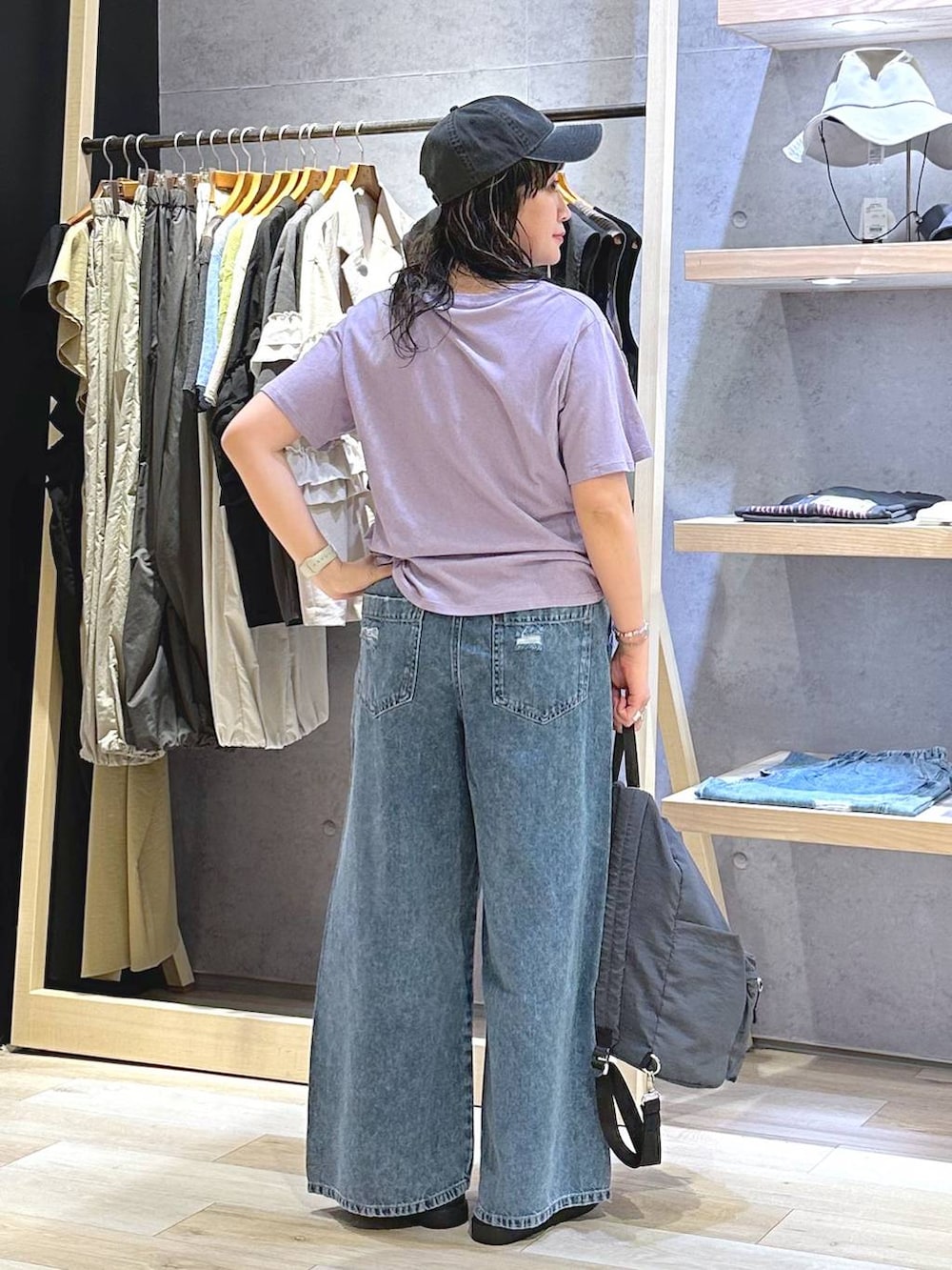 ブルー系のデニムパンツ、ブラウン系のサンダル、グレー系のバックパック/リュックを着用したレディースの夏コーディネートの4枚目の写真