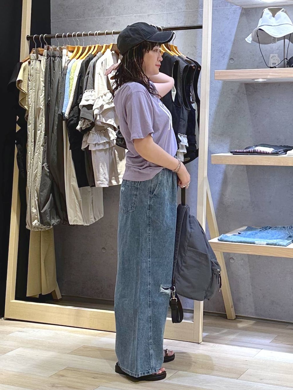 ブルー系のデニムパンツ、ブラウン系のサンダル、グレー系のバックパック/リュックを着用したレディースの夏コーディネートの3枚目の写真