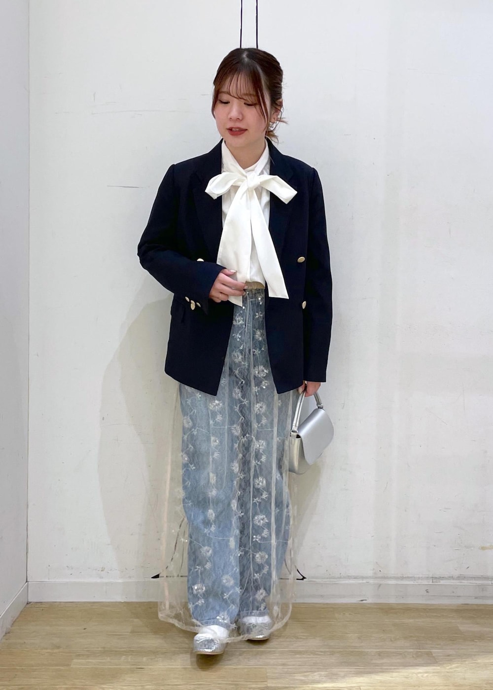 ブルー系のデニムパンツ、ホワイト系のスカート、シルバー系のハンドバッグを着用したレディースの冬コーディネートの3枚目の写真
