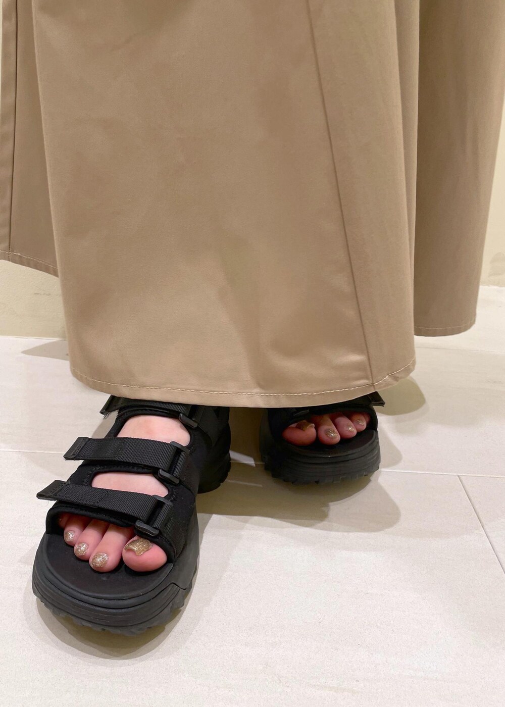 ブラック系のサンダル、ベージュ系のスカート、ホワイト系のシャツ/ブラウスを着用したレディースの夏コーディネートの9枚目の写真