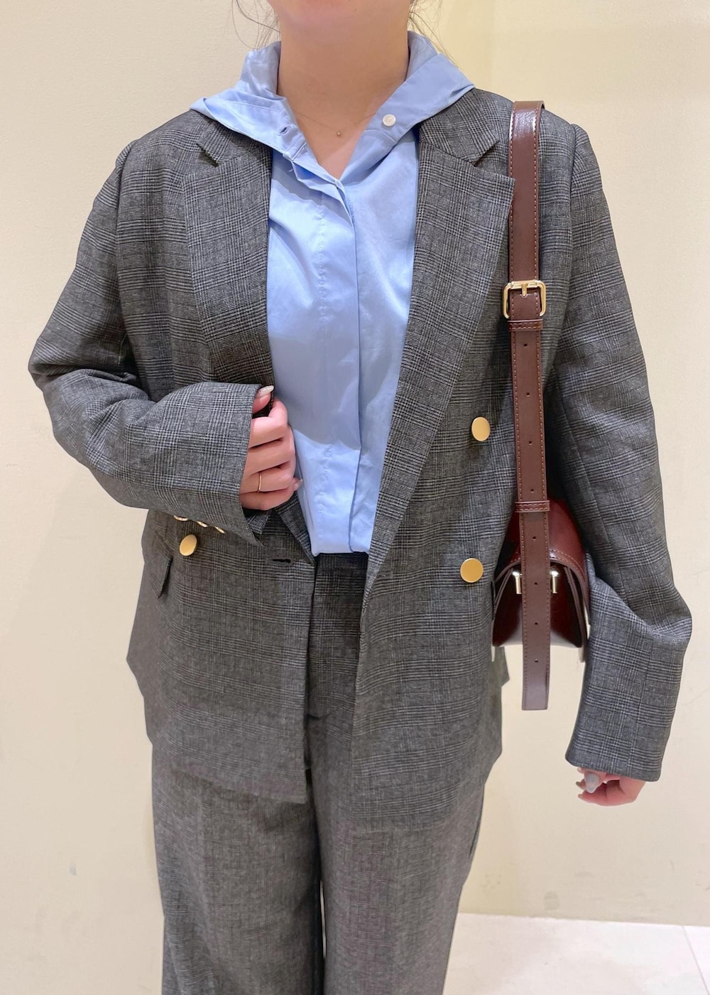 レッド系のショルダーバッグ、グレー系のテーラードジャケット、グレー系のスラックスを着用したレディースの秋コーディネートの6枚目の写真