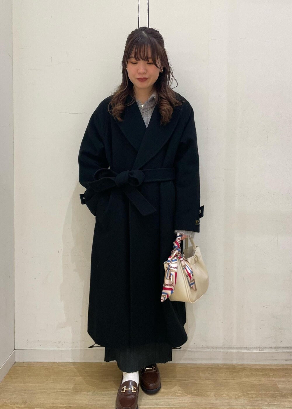 ブラウン系のローファー、グレー系のスカート、ブラック系のチェスターコートを着用したレディースの冬コーディネートの3枚目の写真