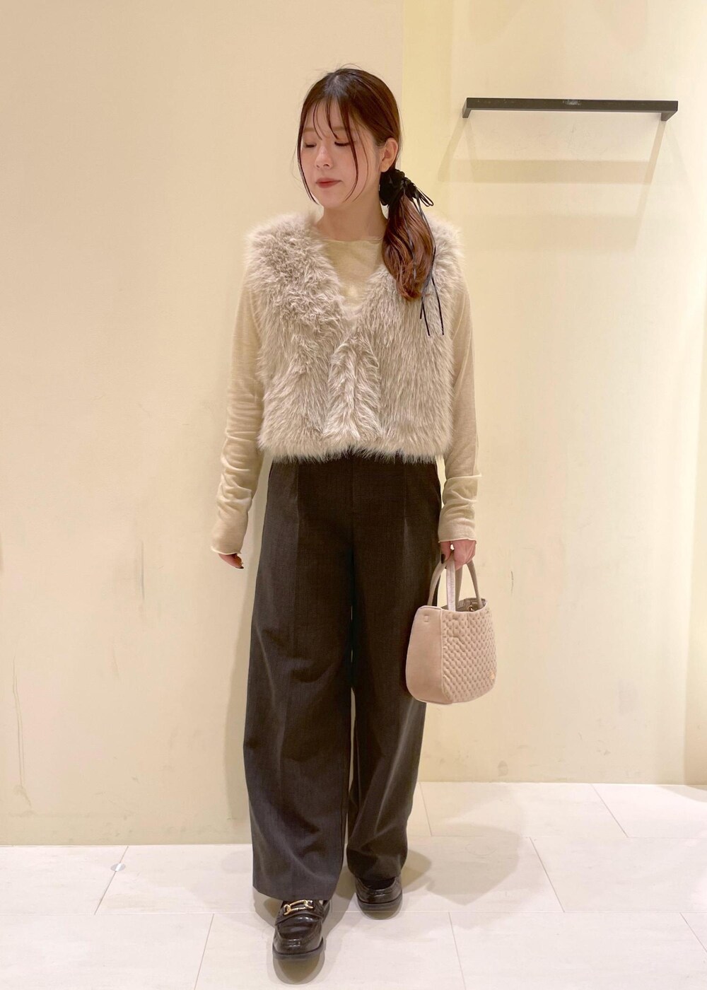 ブラック系のスラックス、ベージュ系のTシャツ/カットソー、ベージュ系のベストを着用したレディースの秋コーディネートの5枚目の写真